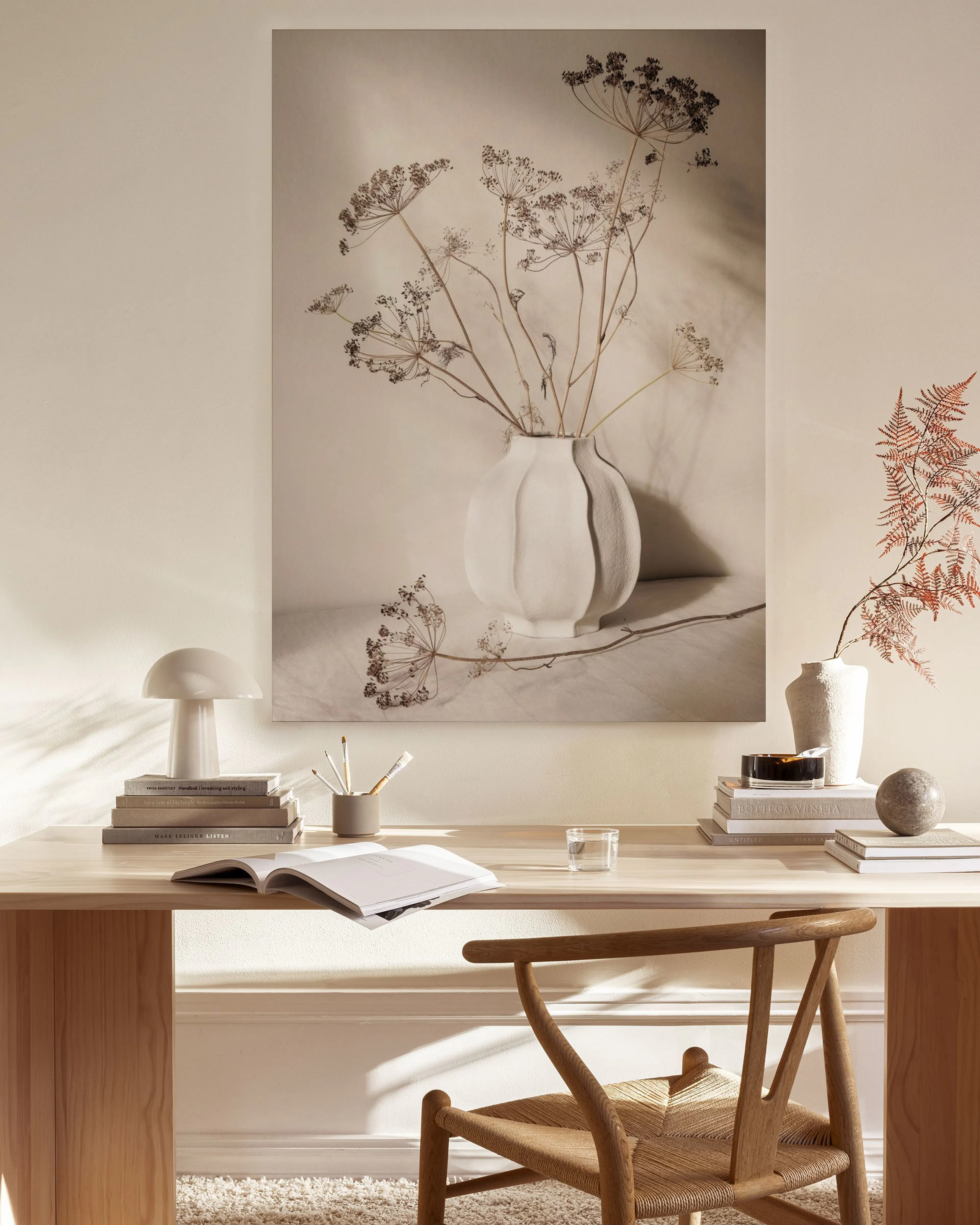 Ein Leinwandbild mit vertrockneten Blüten in einer strukturierten weißen Vase, auf einer hellen Oberfläche stehend.