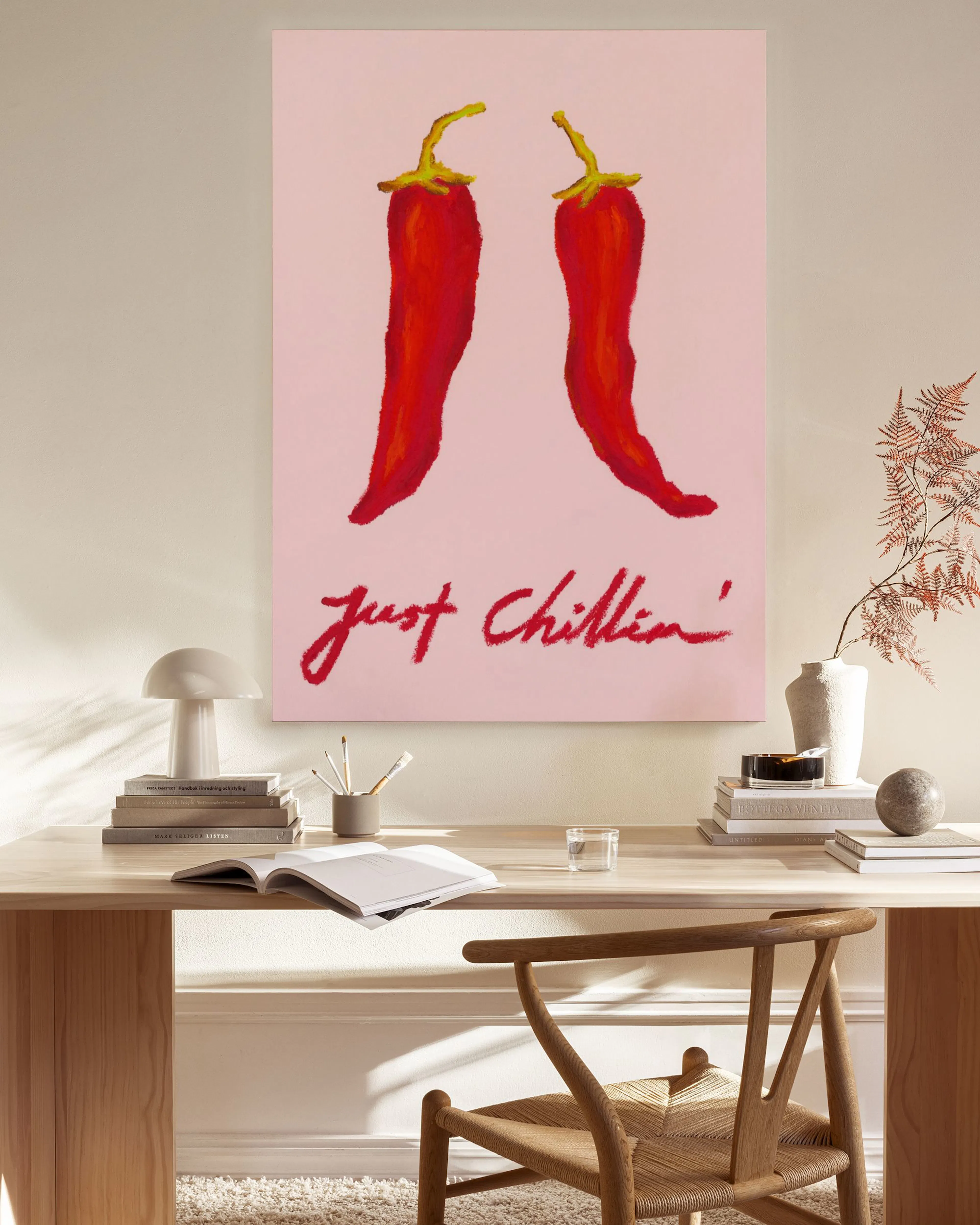 A canvas print with two red chili peppers on a light pink background, with the words Just Chillin in red script below.