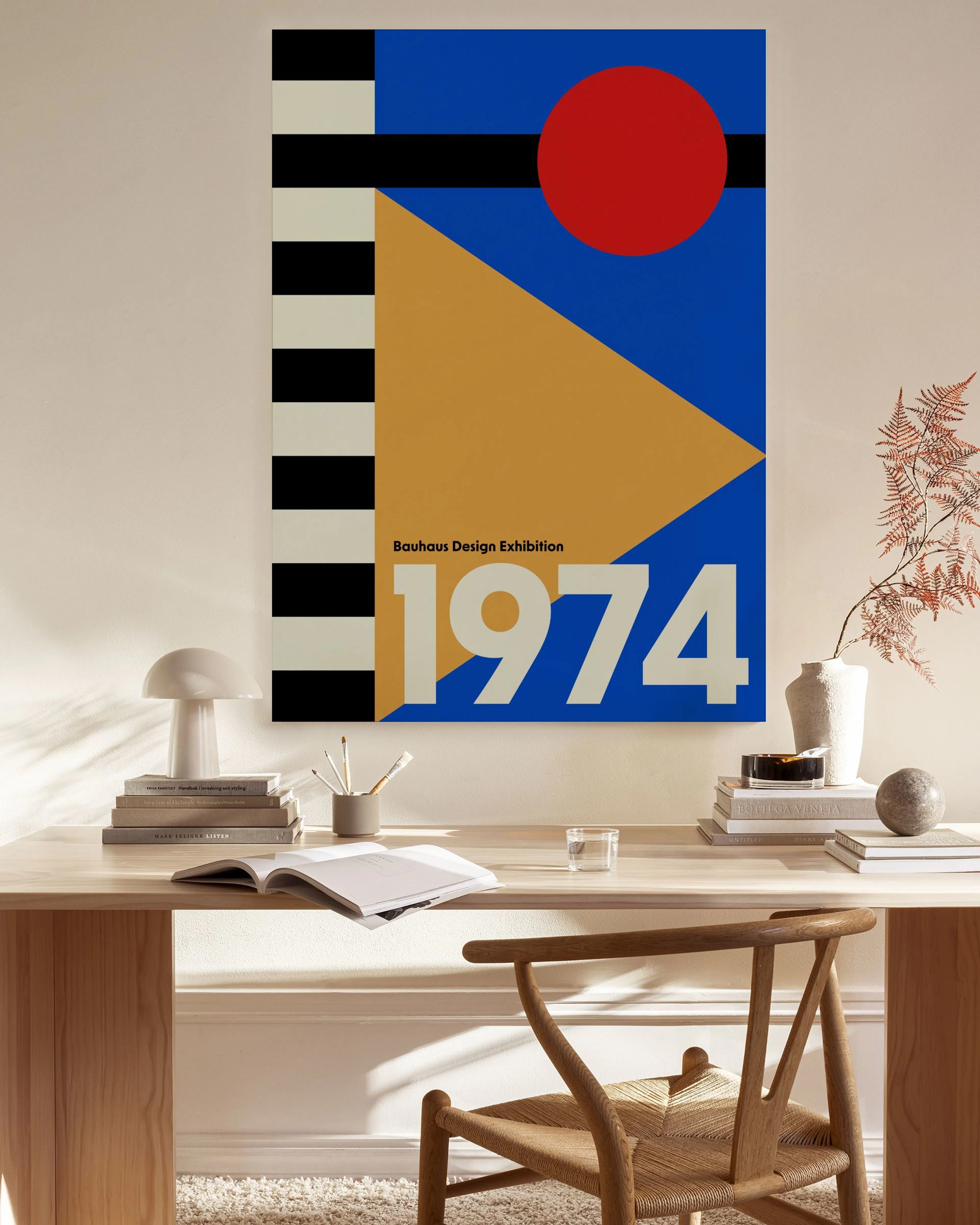 A Bauhaus-style canvas print with a red circle, yellow triangle, and black and white stripes on a blue background, hanging in a 