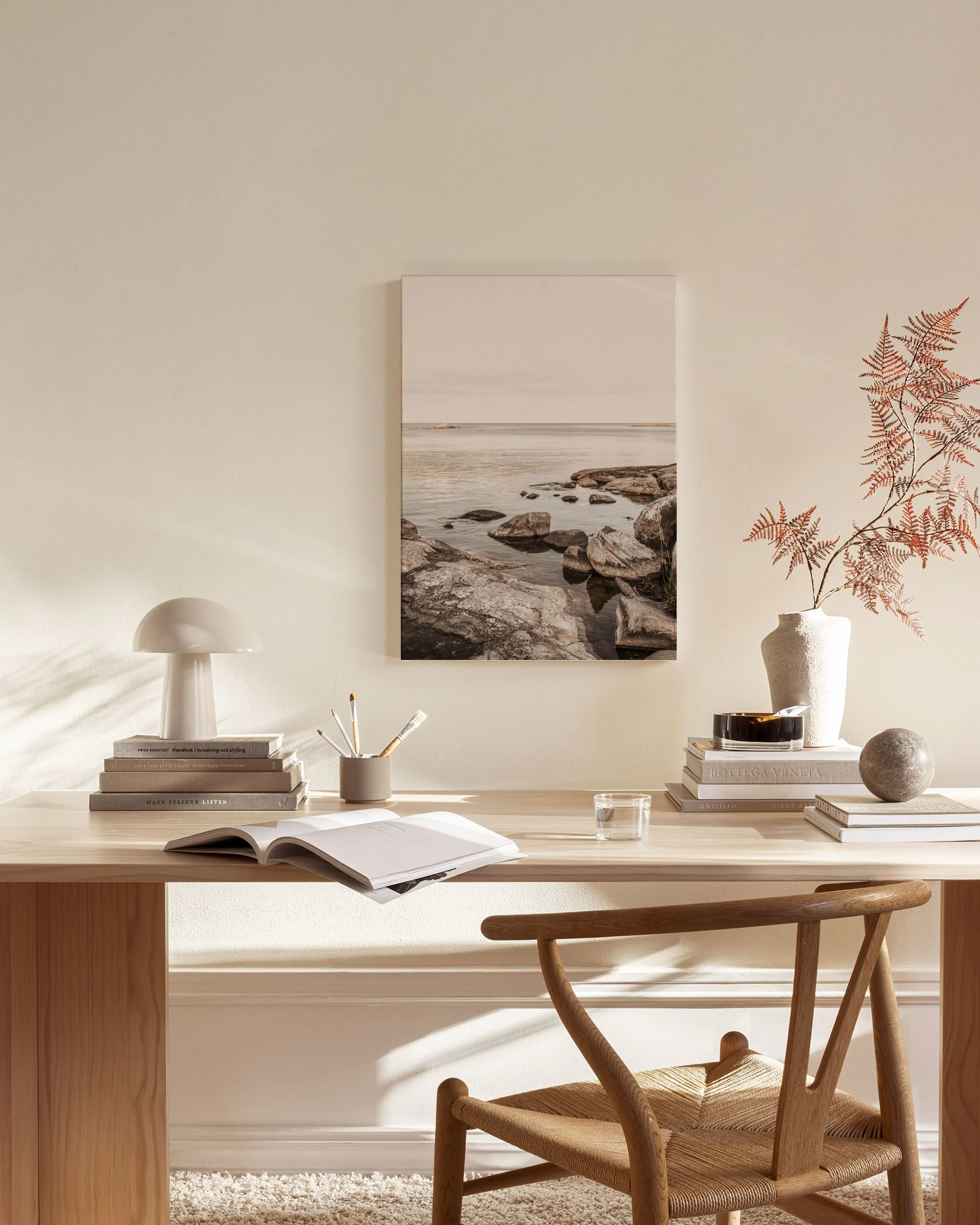 Toile de paysage marin rocheux aux teintes naturelles, suspendue dans un salon moderne au mobilier en bois clair.
