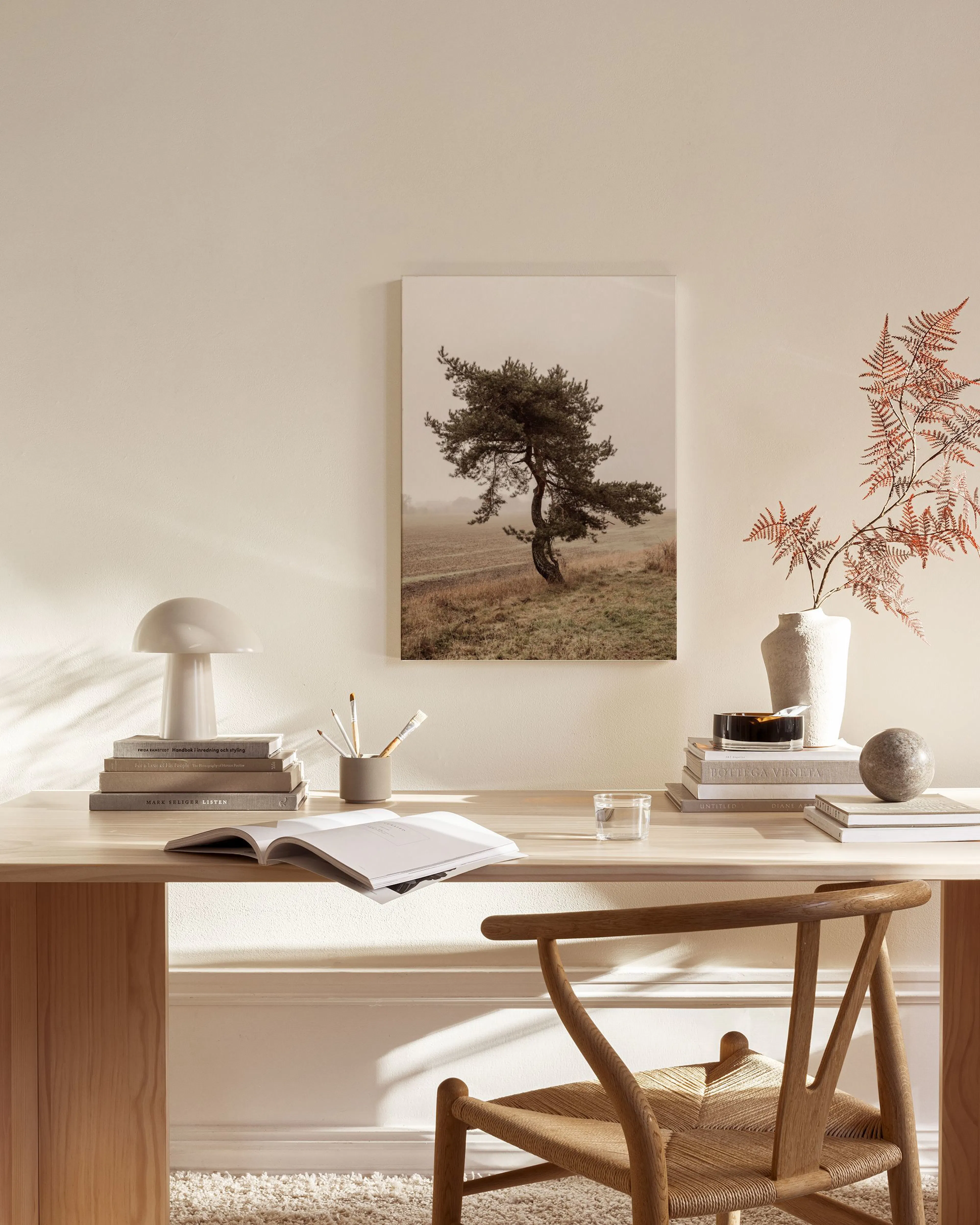 Toile dun arbre solitaire dans un champ brumeux, accrochée au-dessus dun banc en bois dans un salon scandinave.