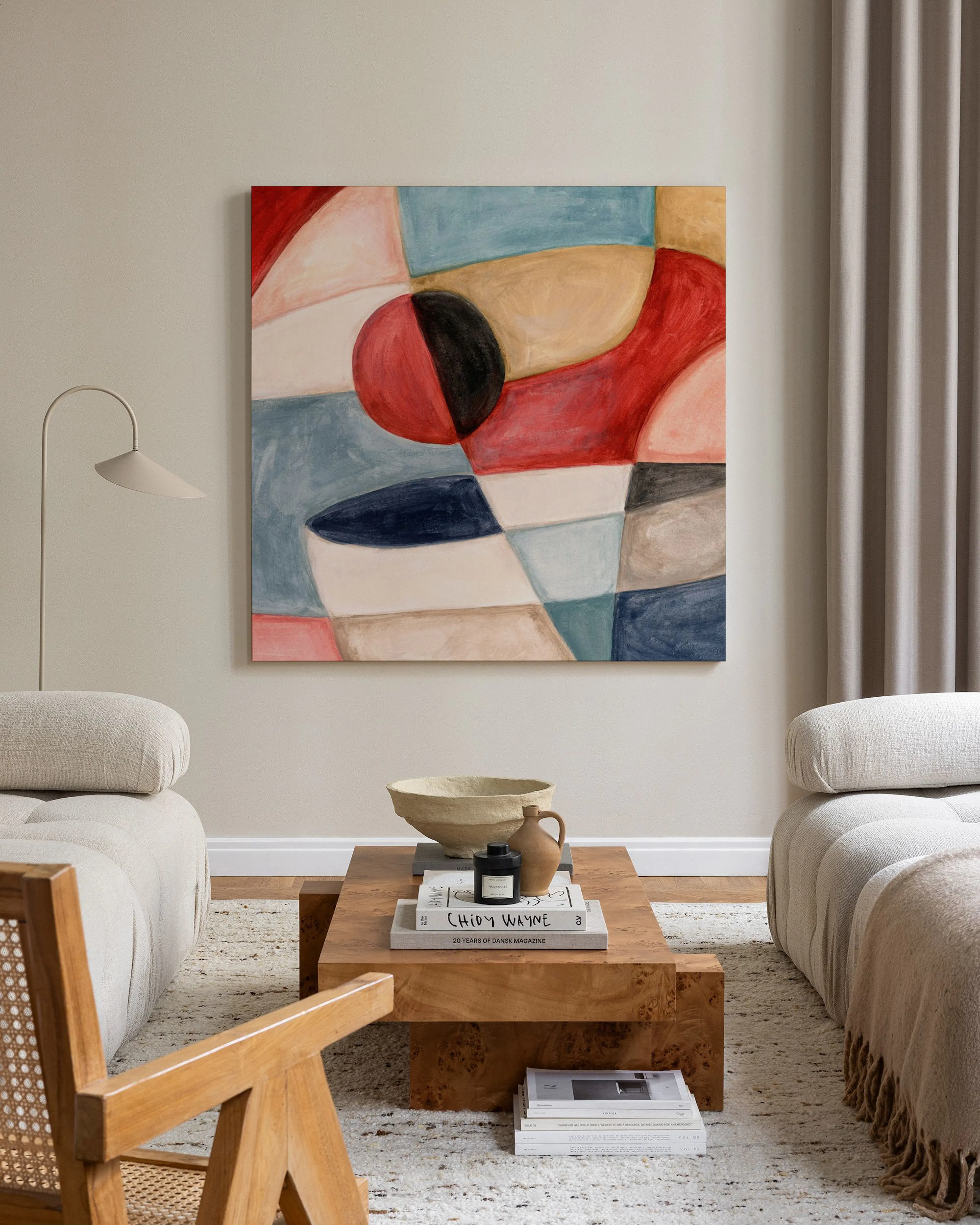 Stampa su tela astratta con forme geometriche e organiche in rosso, blu, beige e nero, appesa sopra un mobile basso in un salott