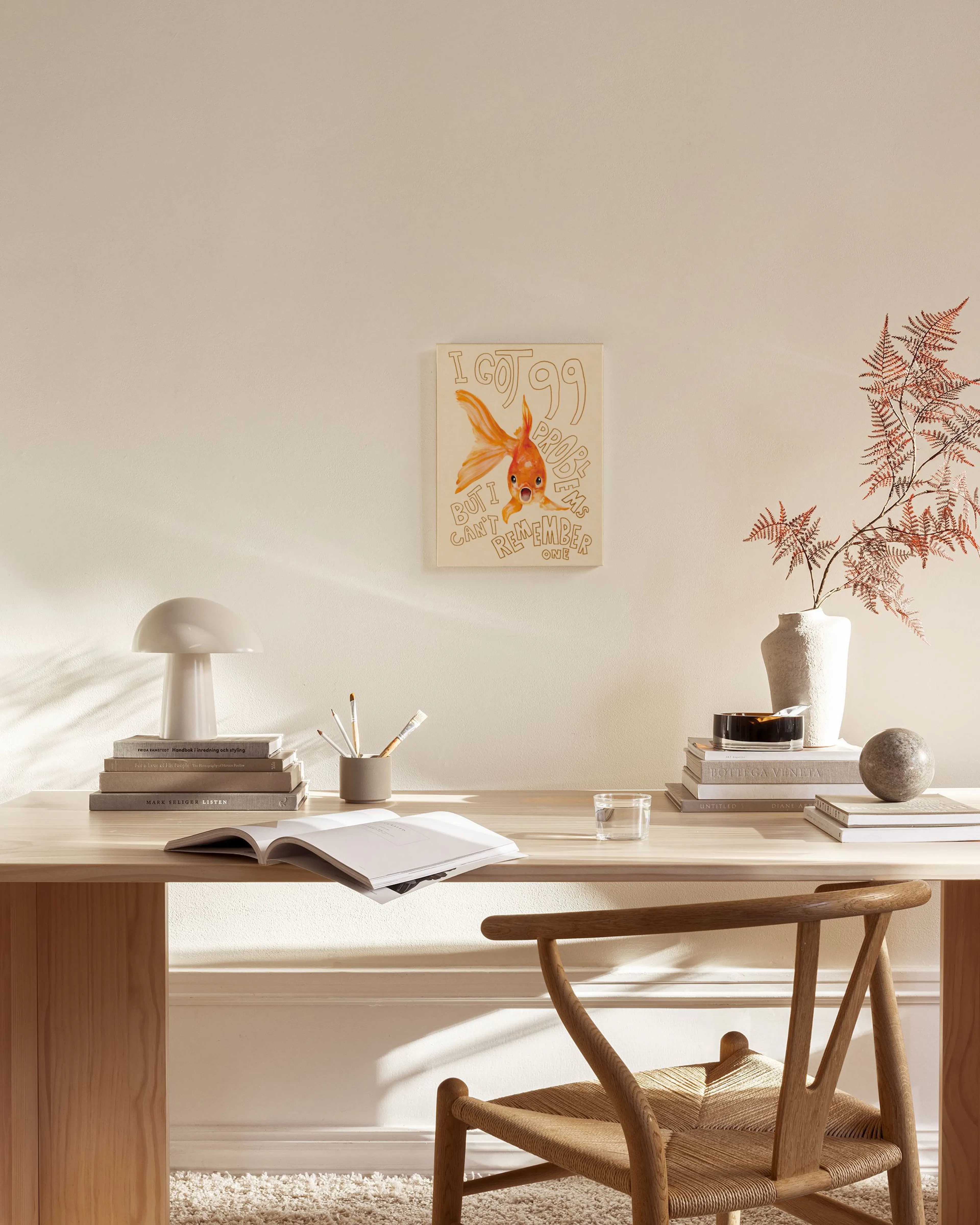 A canvas print of an orange goldfish with the text I got 99 problems but I cant remember one, hanging in a neutral living room a