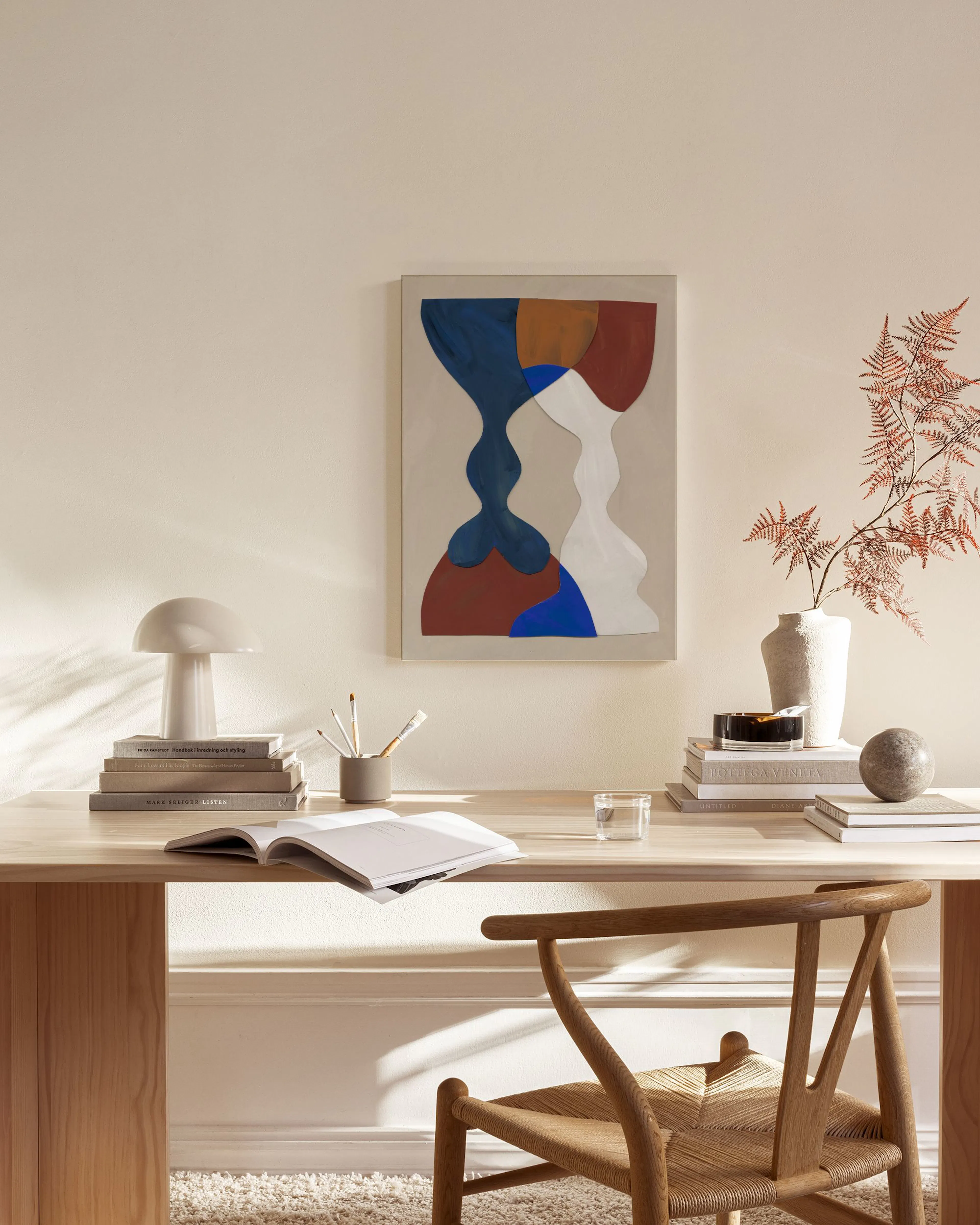 Canvas met abstracte zandlopervormen in blauw, wit en bruin, hangend in een neutrale woonkamer.