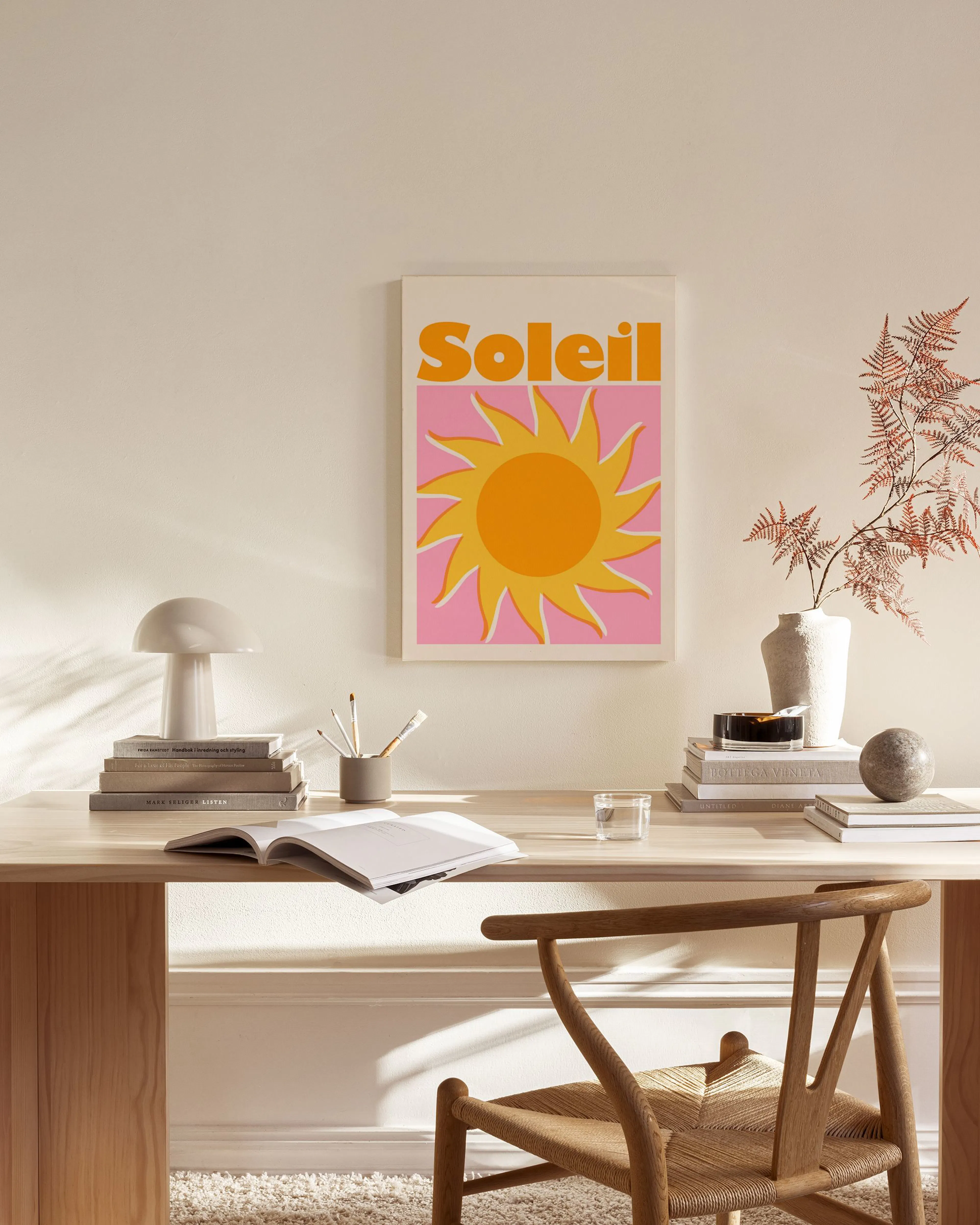 Canvastavla med ordet Soleil och en orange sol på rosa bakgrund, hänger i ett ljust vardagsrum.