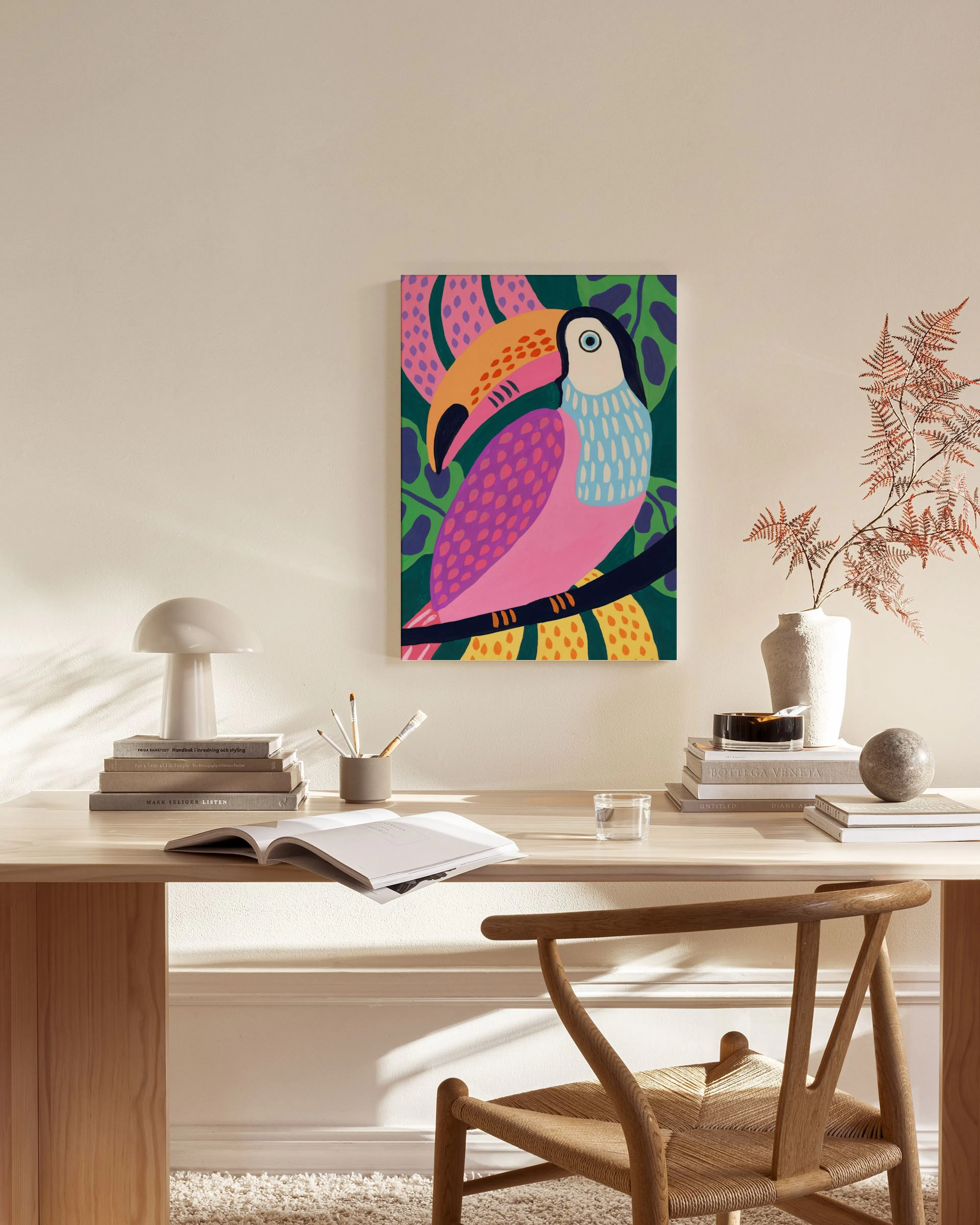Vibrant toucan canvas print with pink and blue plumage, yellow beak, on a dark green leafy background, hanging in a bright livin