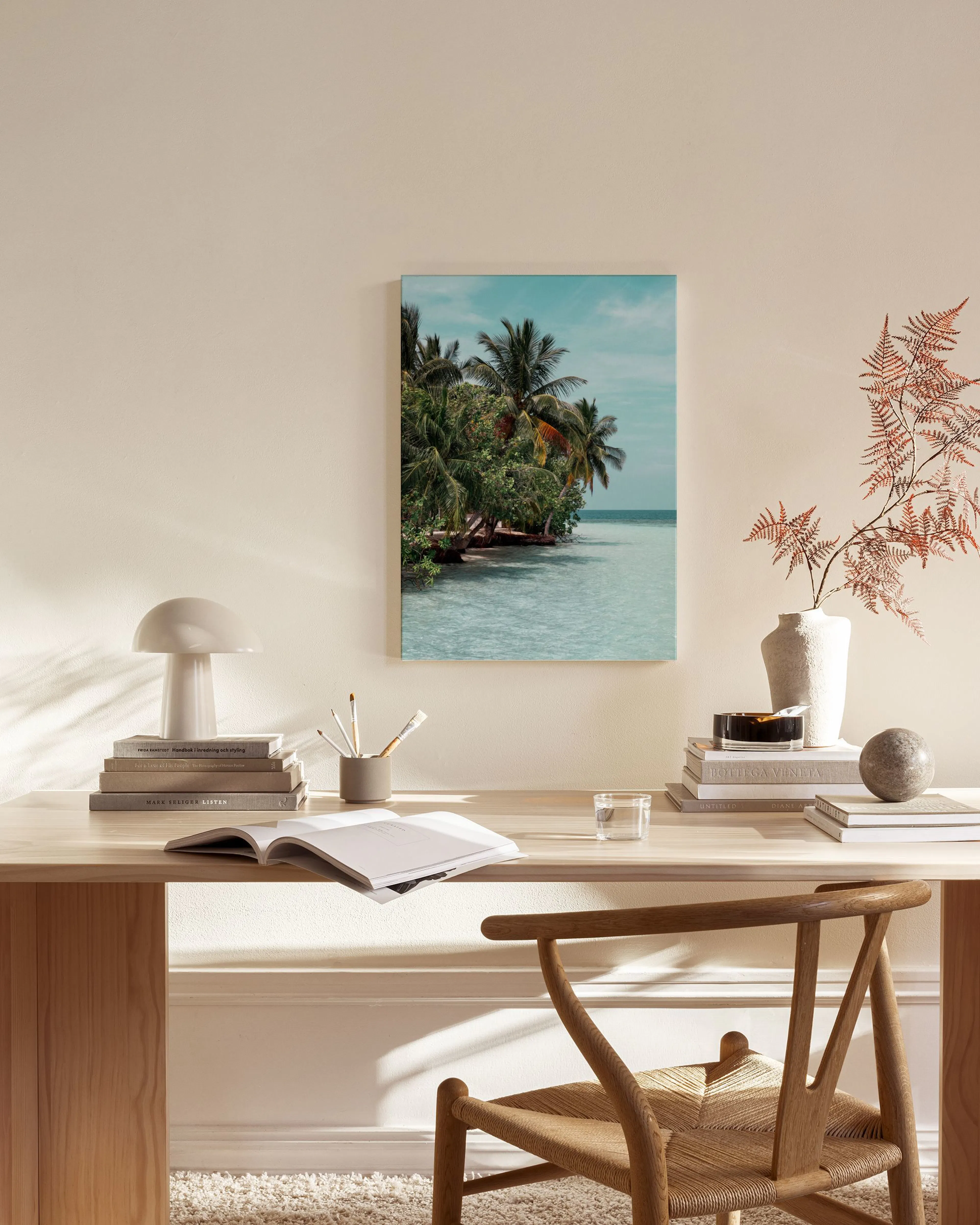 Tela decorativa de uma praia tropical com palmeiras verdes e água azul-clara, pendurada numa sala de estar minimalista.