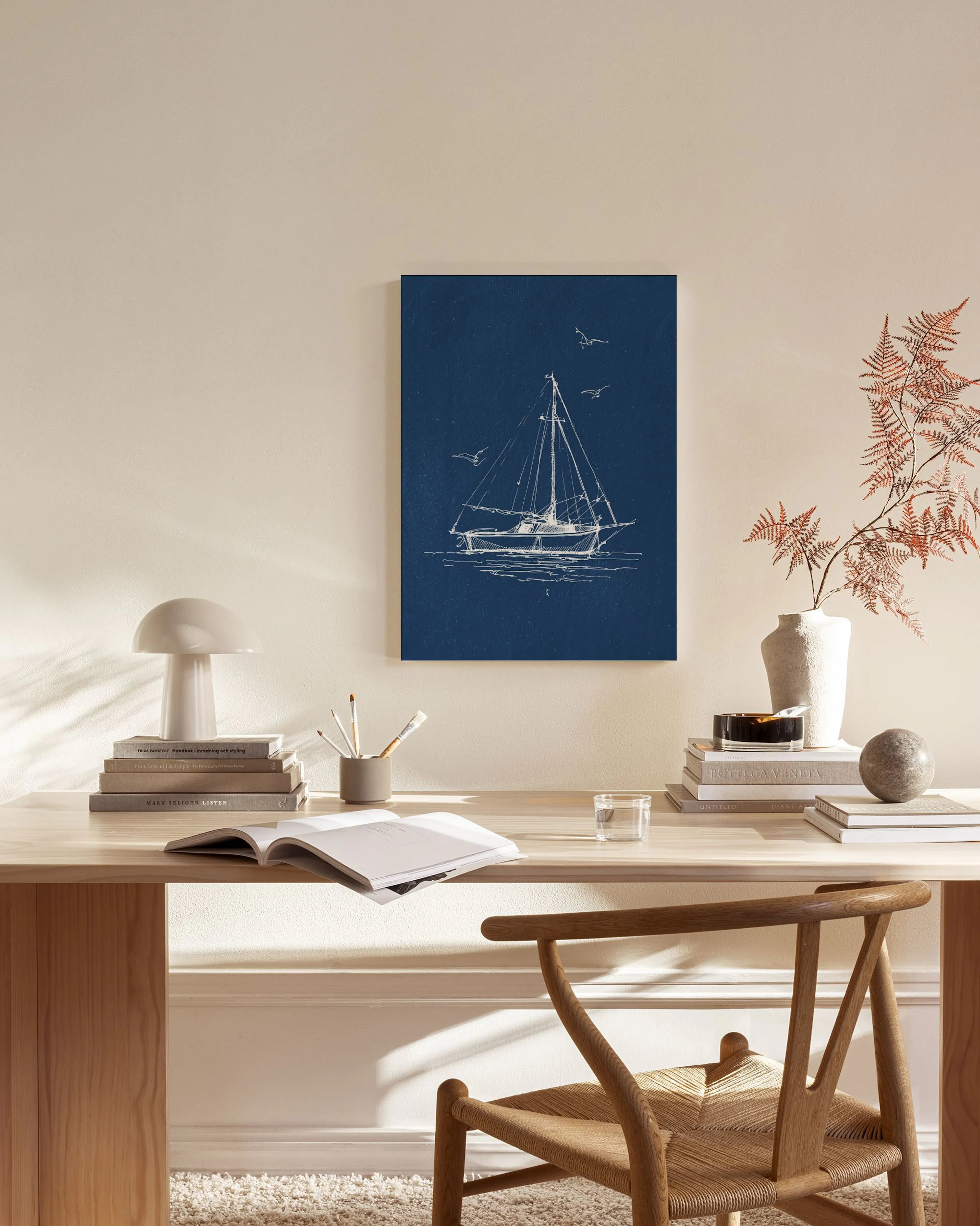 Canvas met witte zeilboot en meeuwen op een donkerblauwe achtergrond, hangend in een lichte woonkamer.