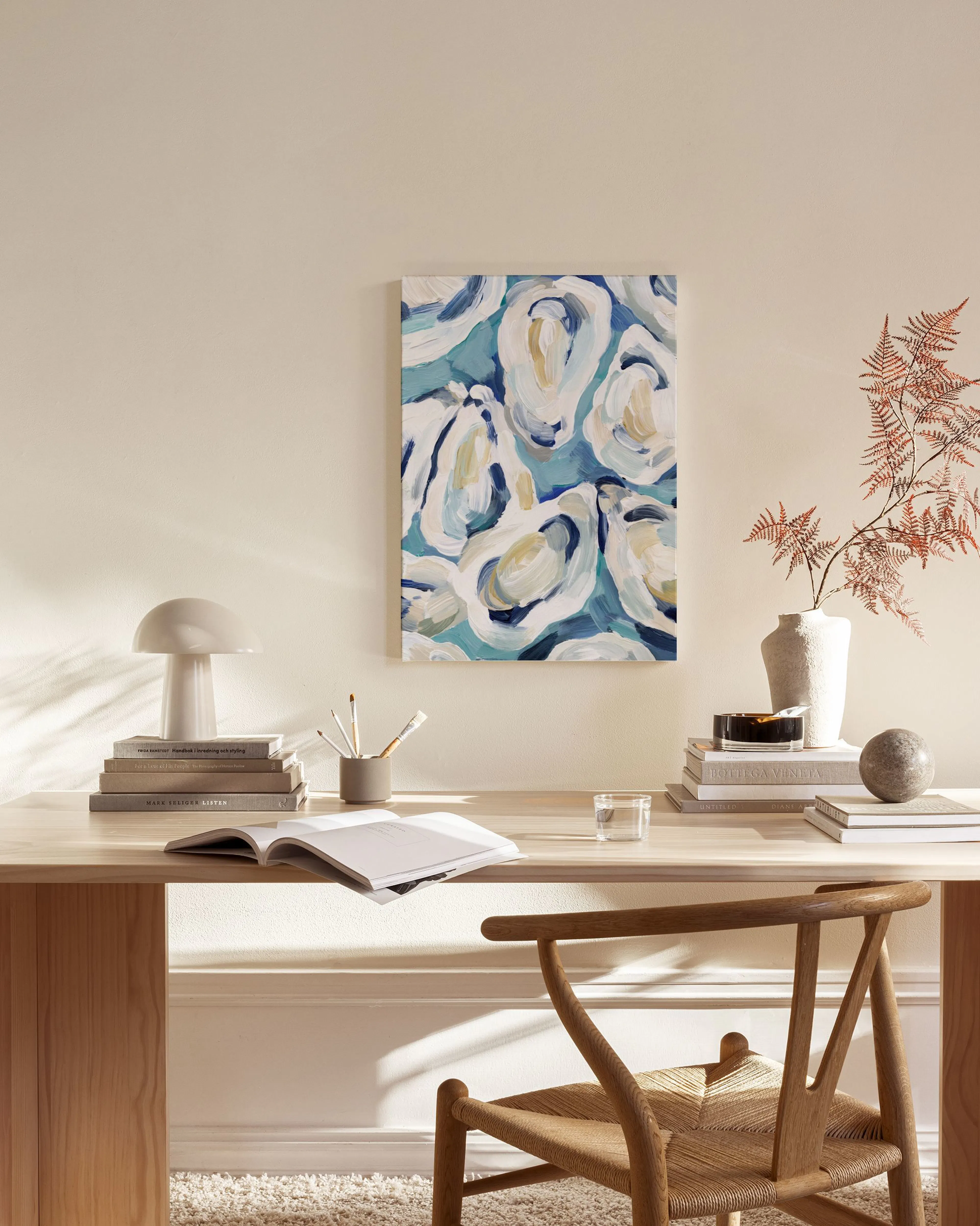Leinwandbild mit abstrakten Austernformen in Blau, Weiß und Gelb in einem hellen Wohnzimmer.