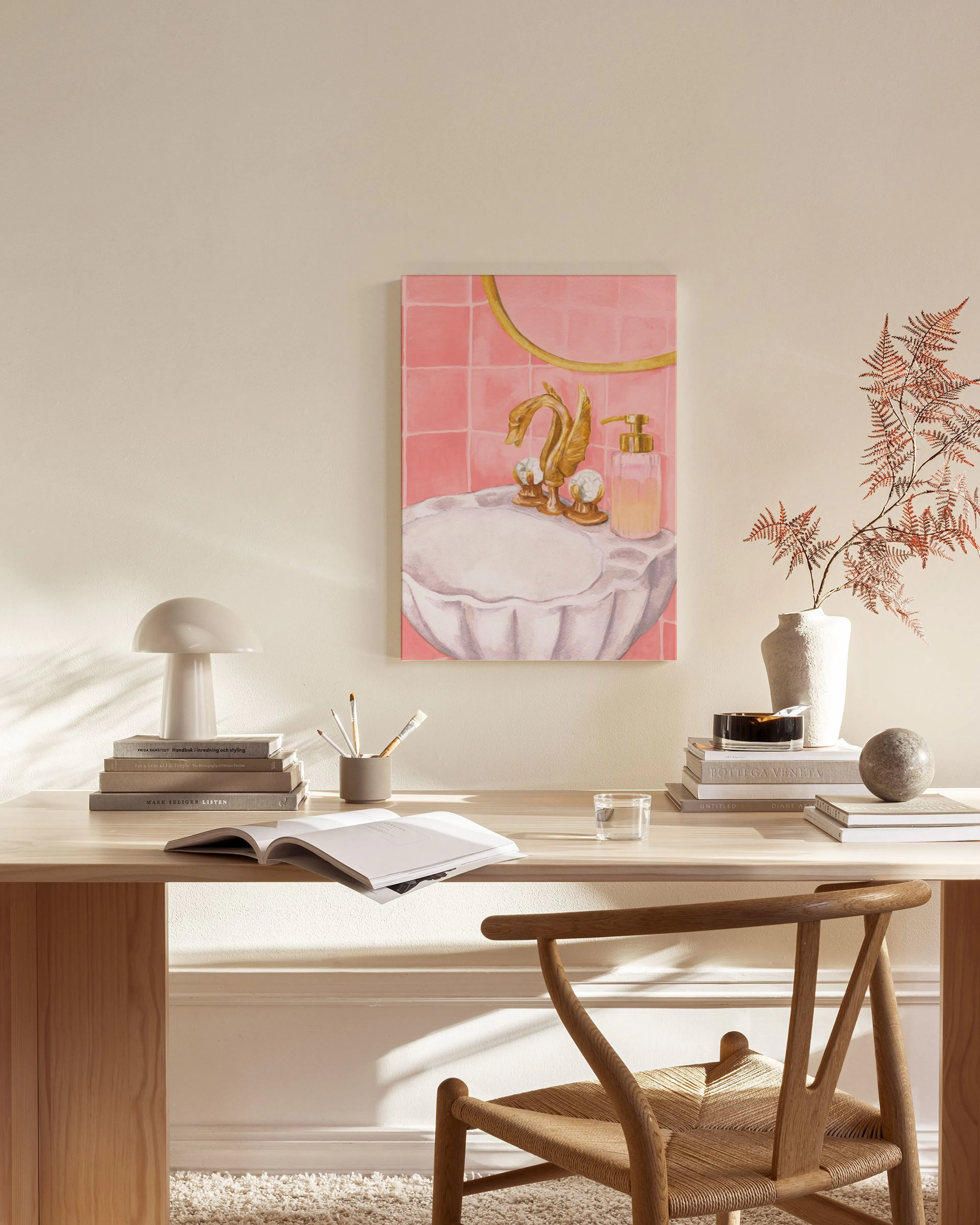 A canvas print of a golden swan faucet and shell sink against pink tiles, displayed in a bright living room.