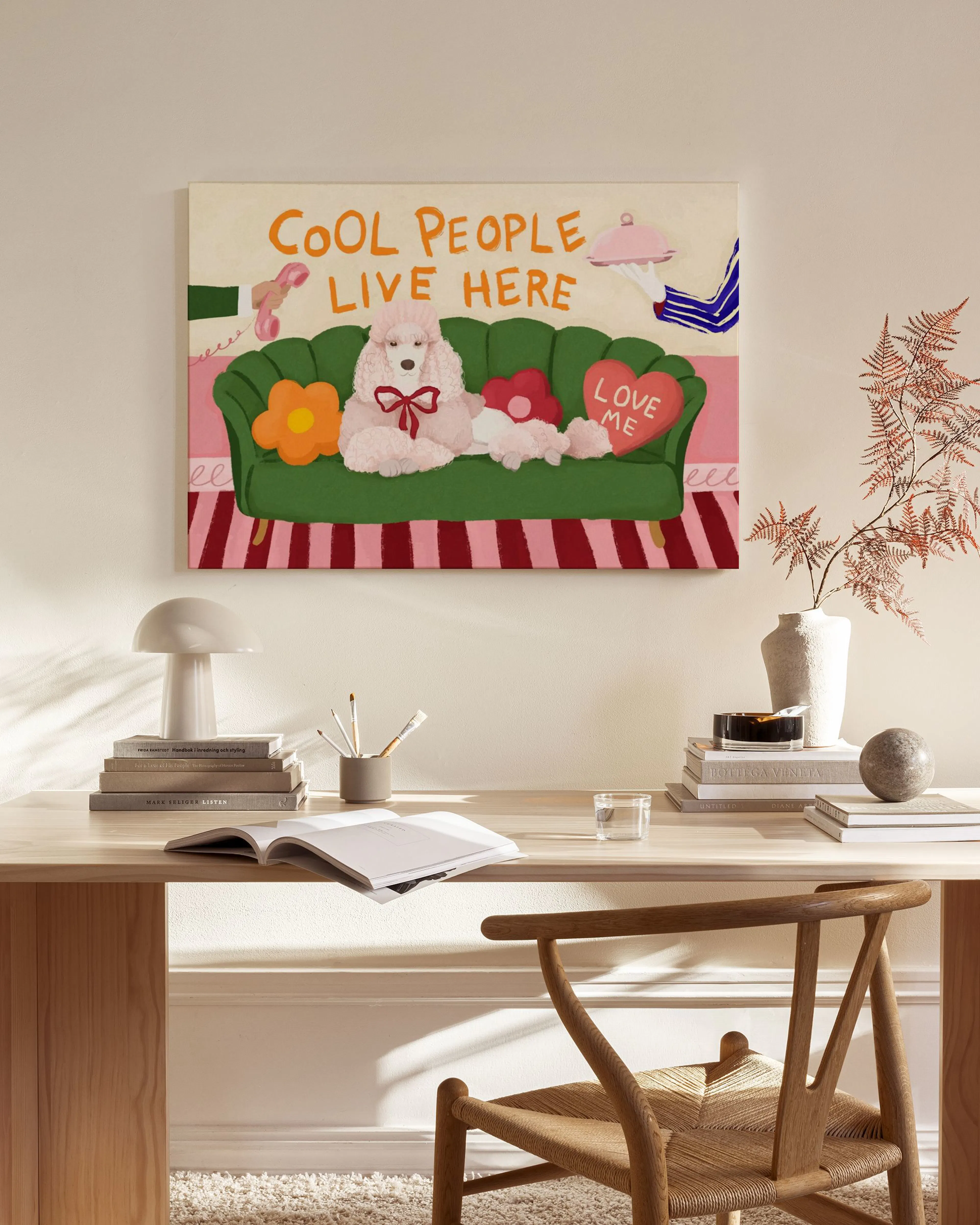 Hauska kanvaasi, jossa vaaleanpunainen koira sohvalla ja teksti COOL PEOPLE LIVE HERE, ripustettuna olohuoneen seinälle.