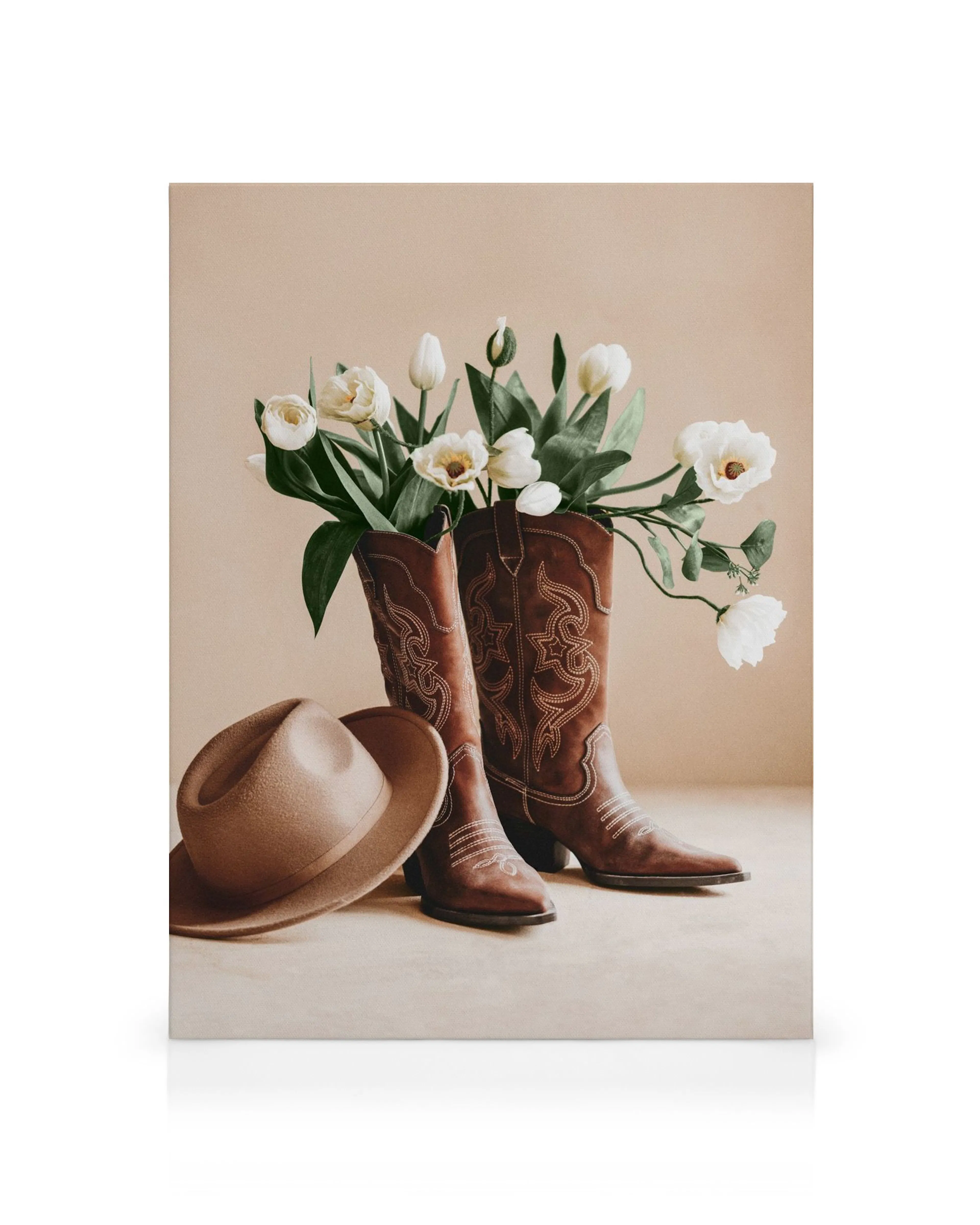 Botas vaqueras marrones con flores blancas y un sombrero de fieltro, estilo campestre.