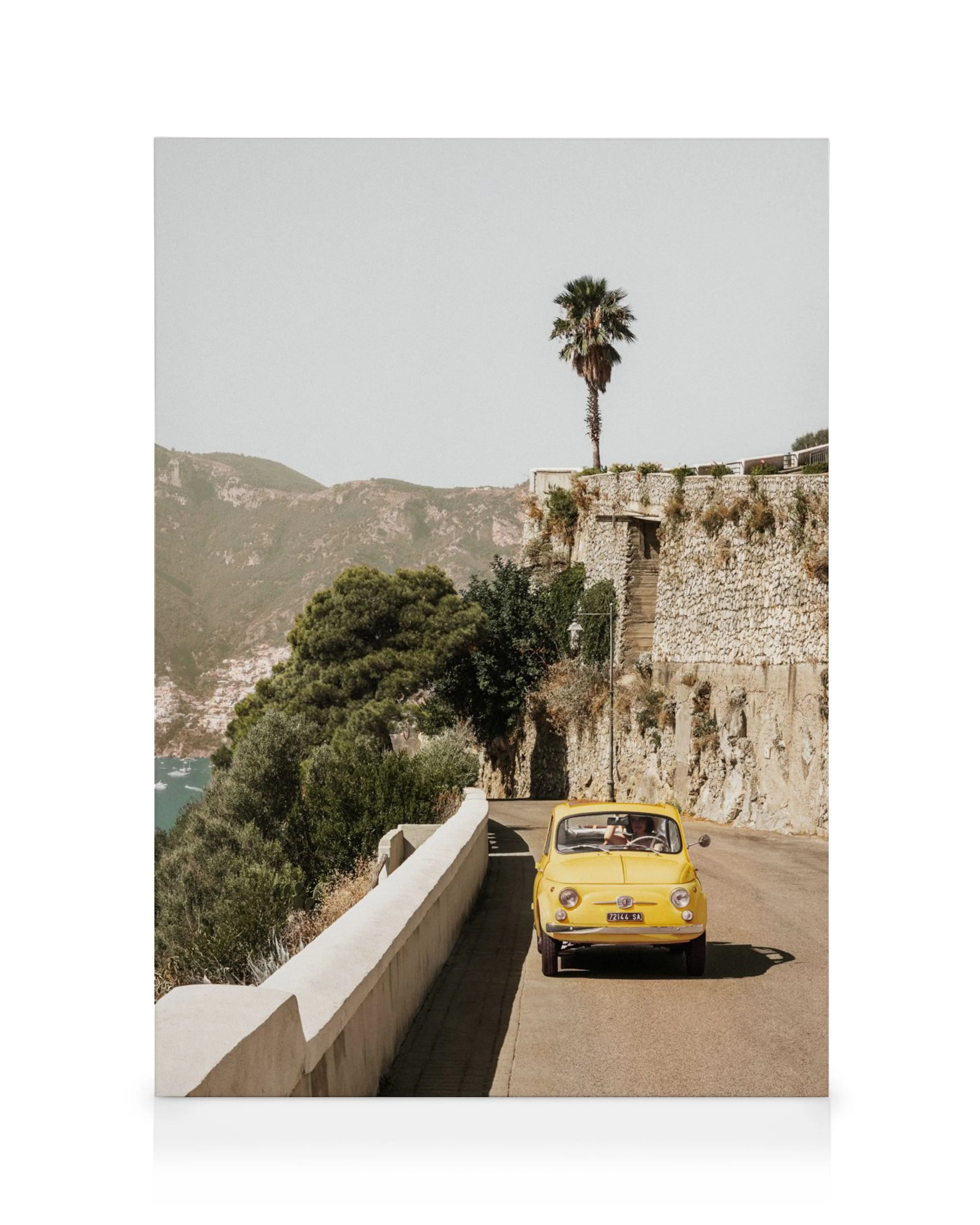 Coche amarillo vintage en carretera costera de Amalfi, Italia, con muro de piedra y palmera