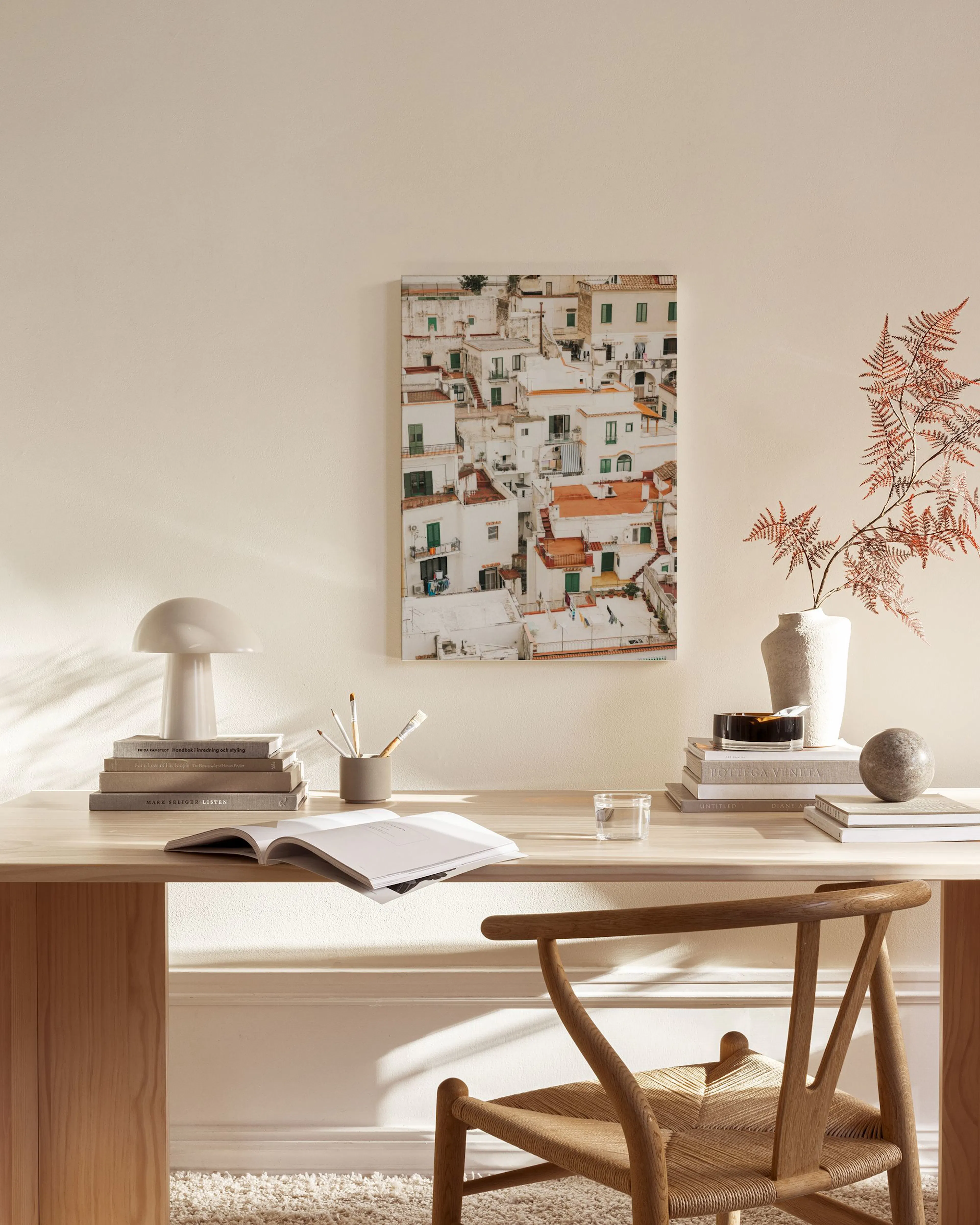 Leinwandbild mit Ansicht weißer Häuser mit grünen Fensterläden und orangefarbenen Dächern, hängend über einem Sideboard.