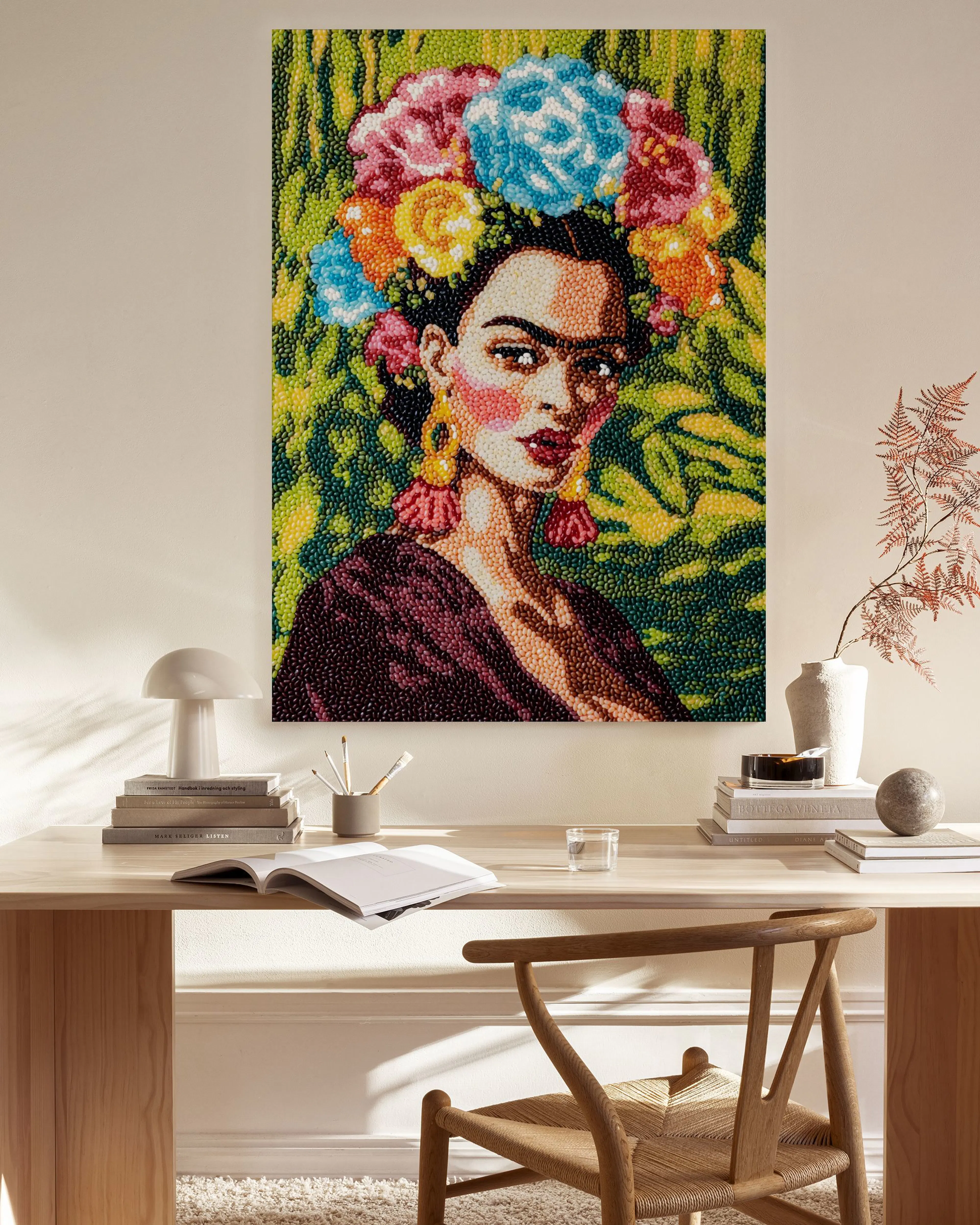 Leinwandbild mit Frida Kahlo-Porträt vor grünem Hintergrund, hängend in einem hellen Wohnzimmer über einem Sideboard.