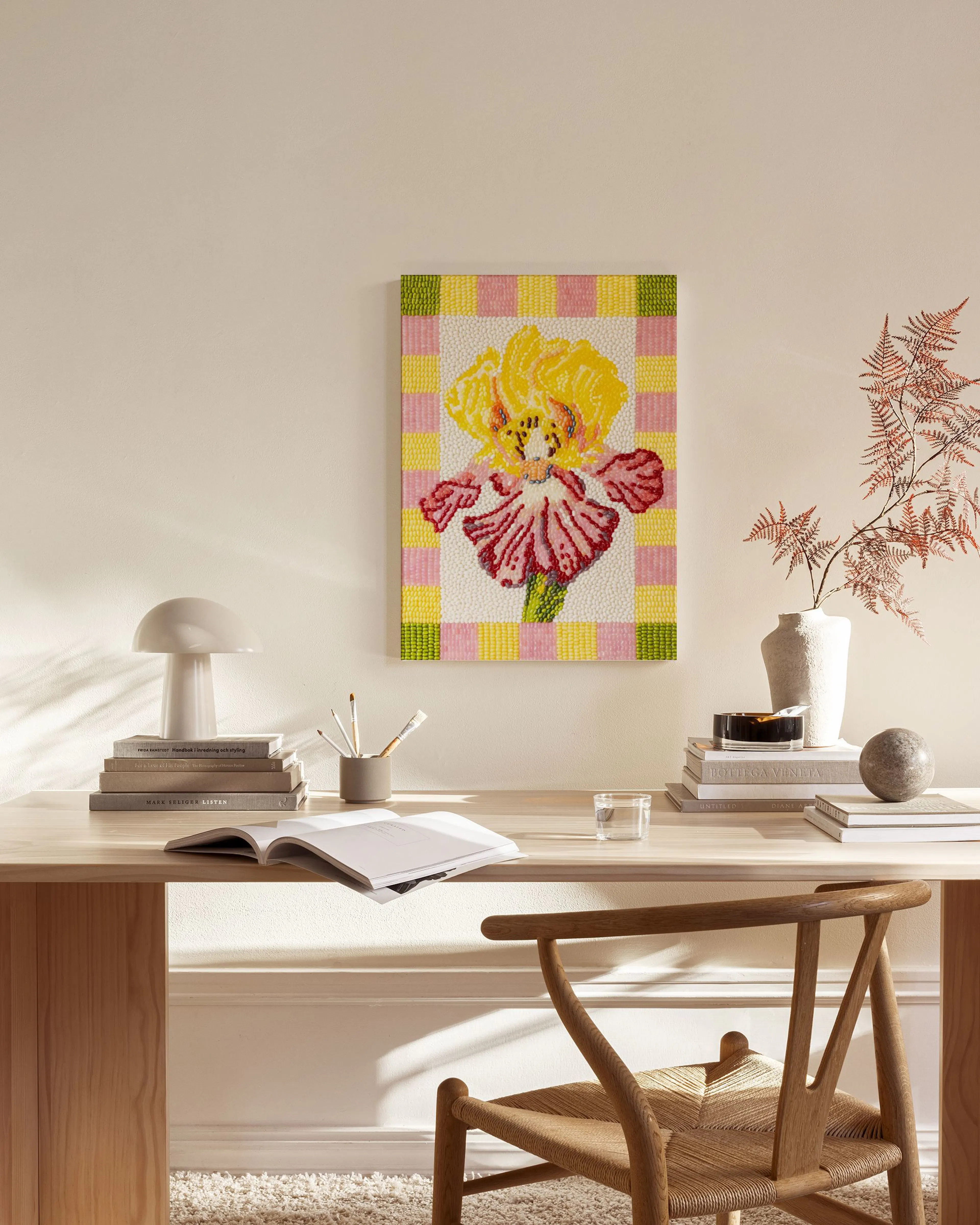 Canvas van een gele en roze iris op een geruite achtergrond, hangend in een neutrale woonkamer.