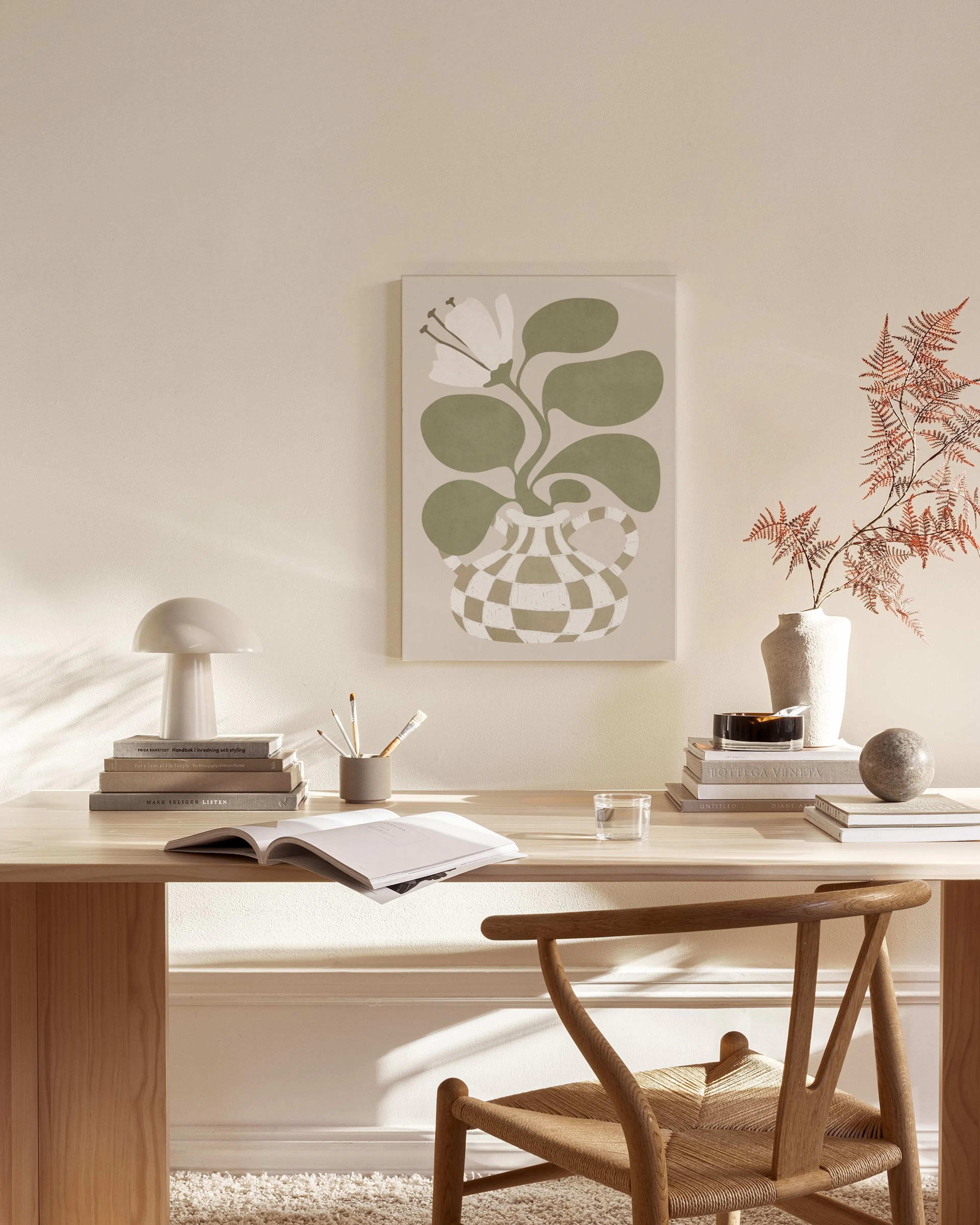 Lienzo con planta verde y flor blanca en jarrón a cuadros, exhibido en una sala con sillón de madera y mesa de centro.