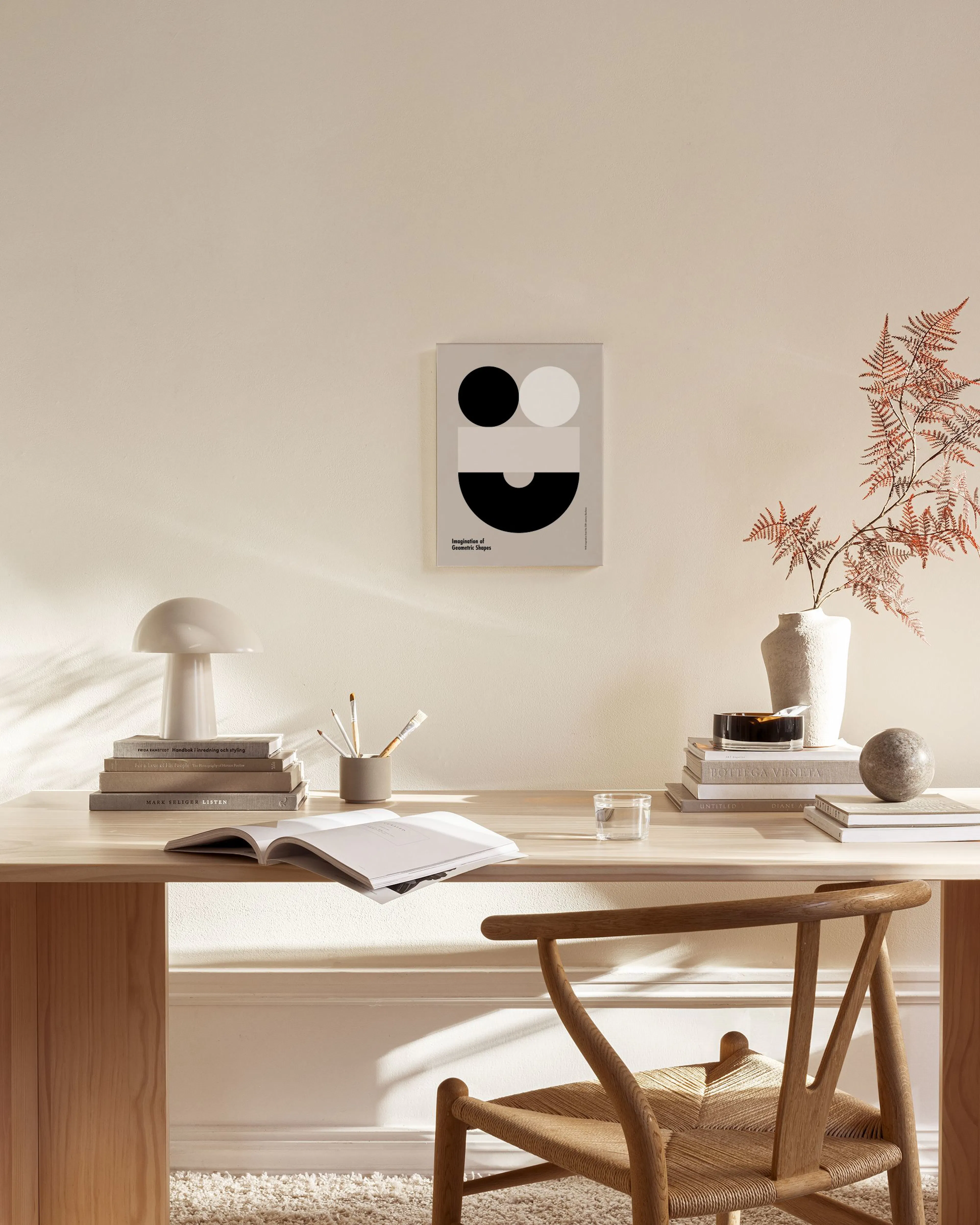 A canvas print with black and white circles, and beige geometric shapes on a light grey background, hanging in a modern living r
