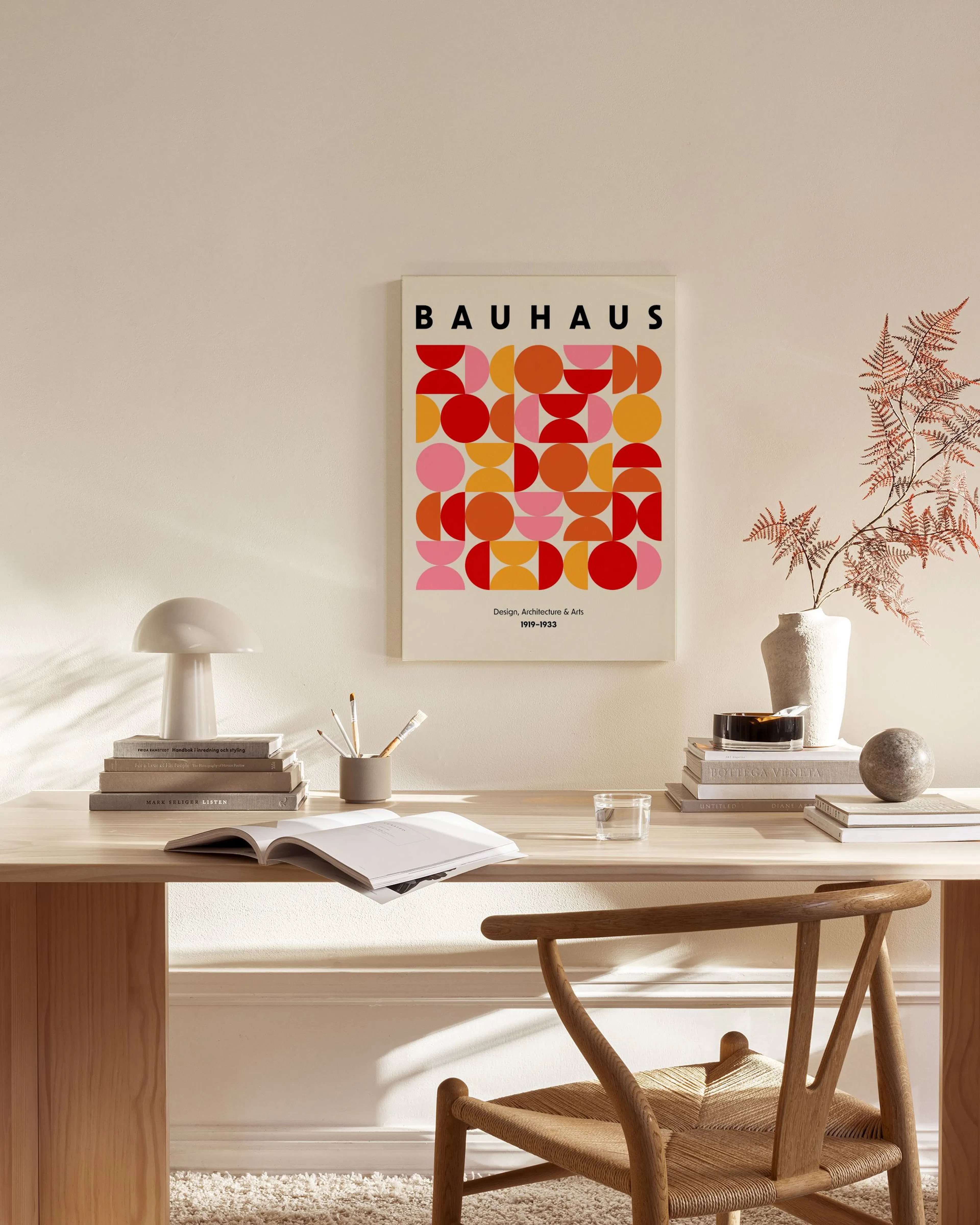 Canvastavla med Bauhaus-affisch i rött, orange och rosa geometriska former, hängande i ett ljust vardagsrum.