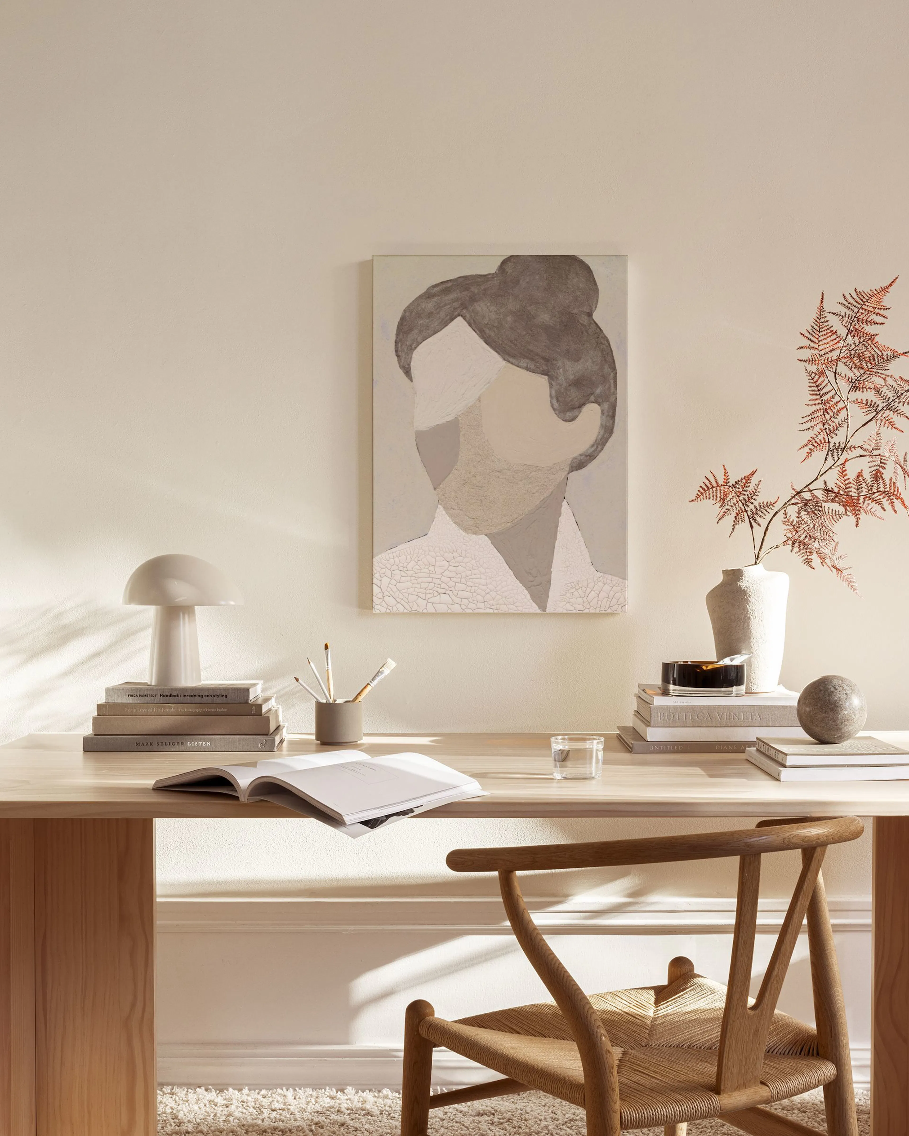 Lienzo abstracto de un rostro femenino en tonos tierra, exhibido en una sala de estar moderna con muebles de madera.
