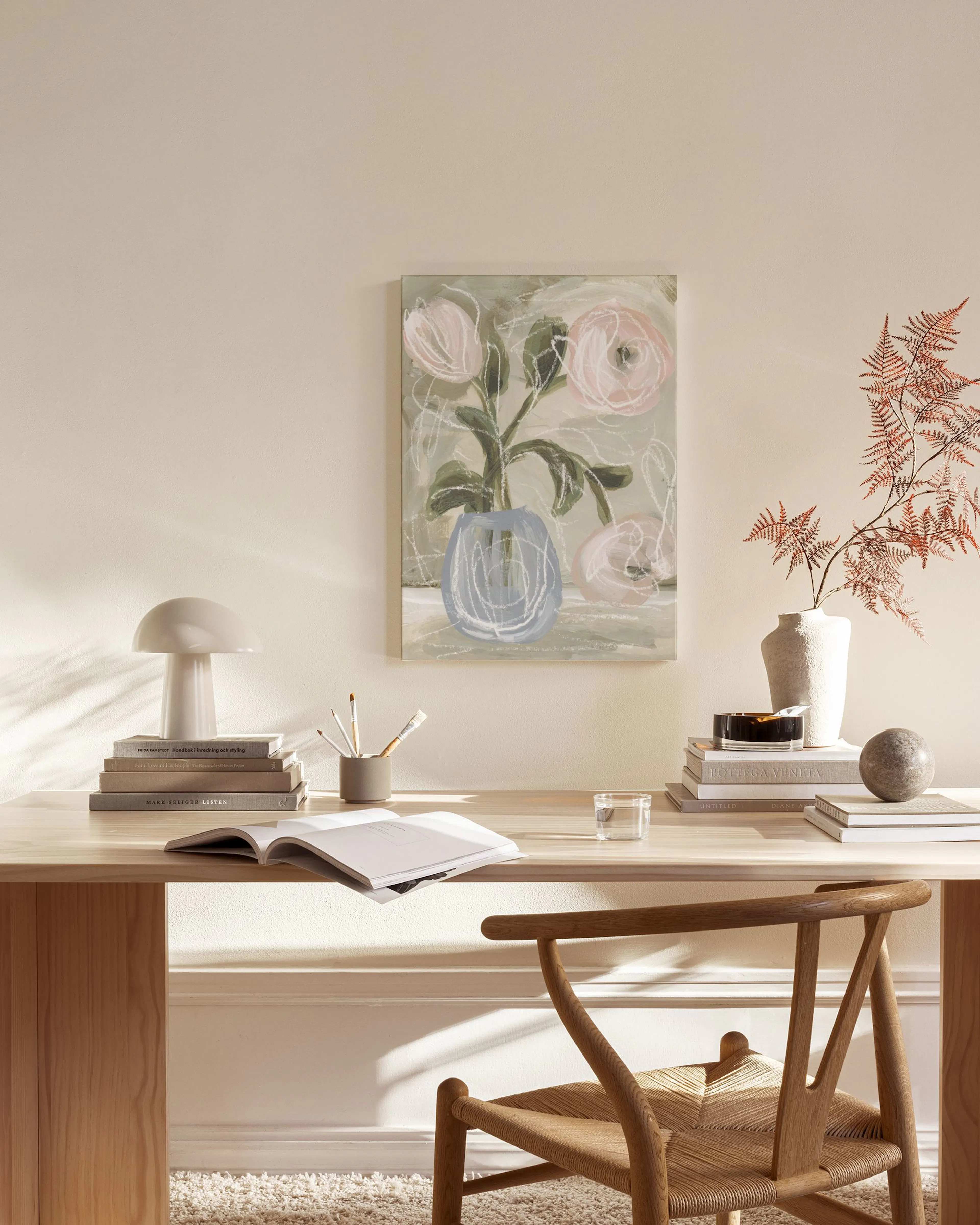 Toile florale de pivoines roses dans un vase bleu sur fond vert pâle, accrochée dans un salon moderne.