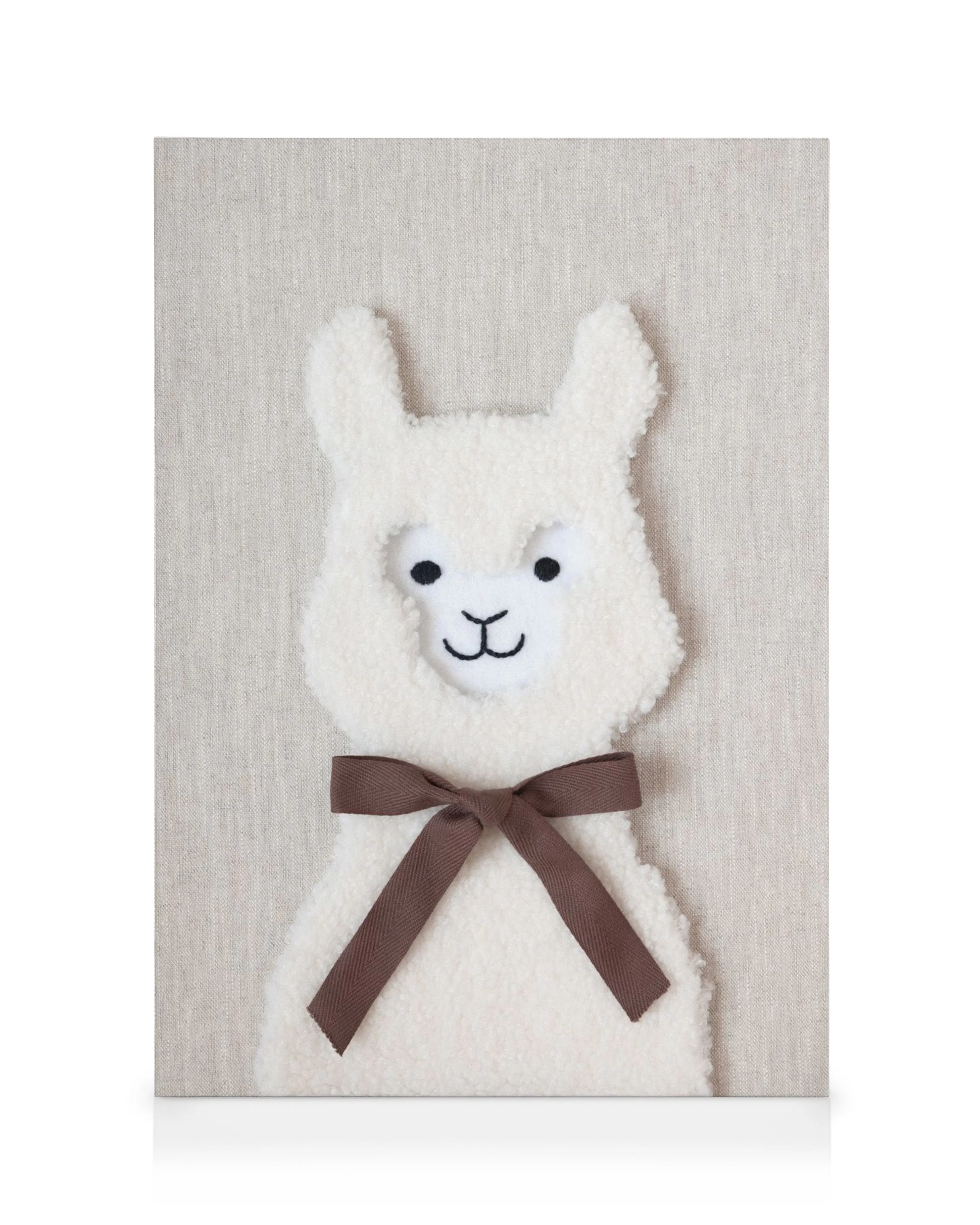 Furry white llama canvas print with a brown bow against a beige background, perfect for a nursery.