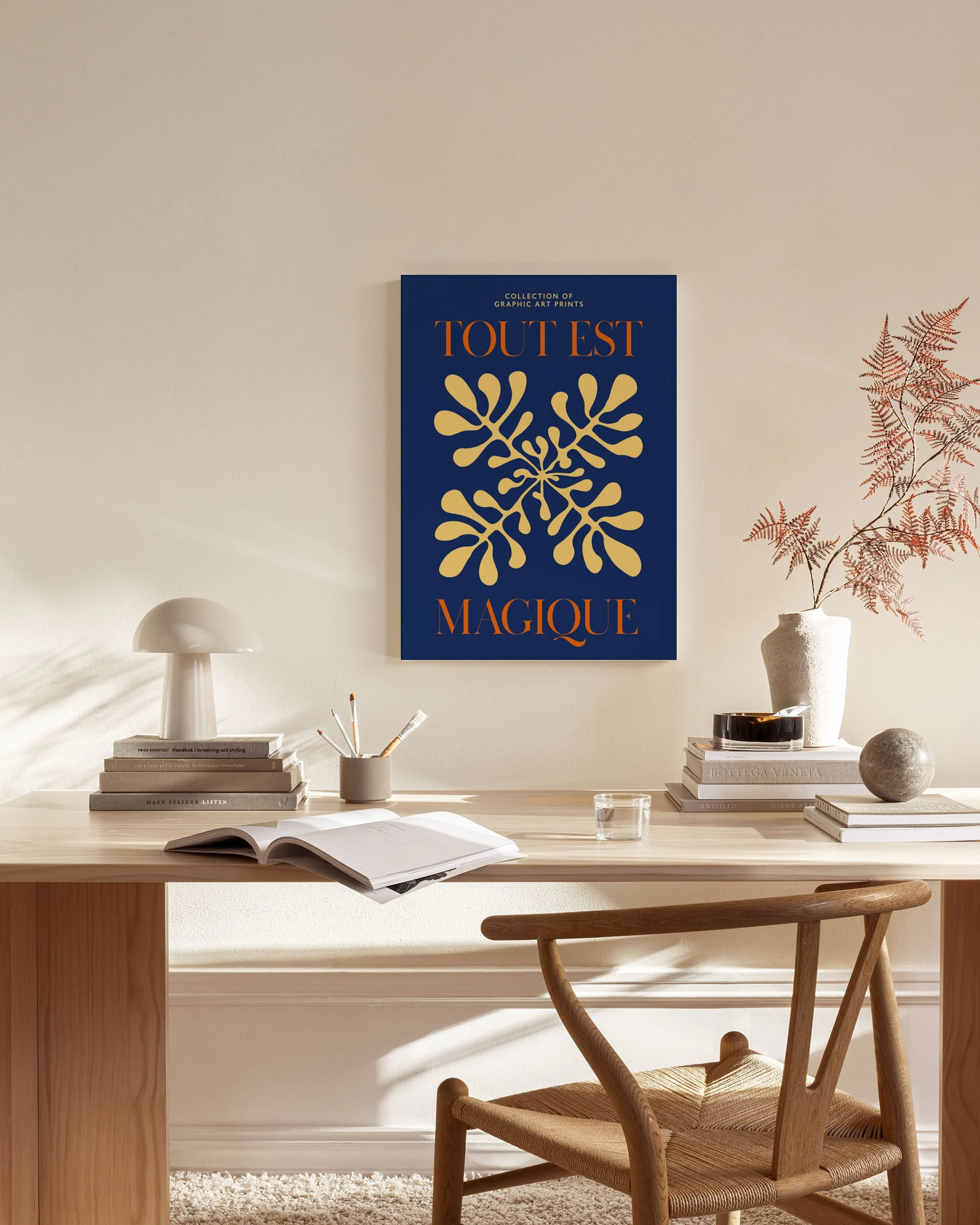 A canvas print with TOUT EST MAGIQUE and yellow leaf patterns on a blue background, displayed in a contemporary living room.