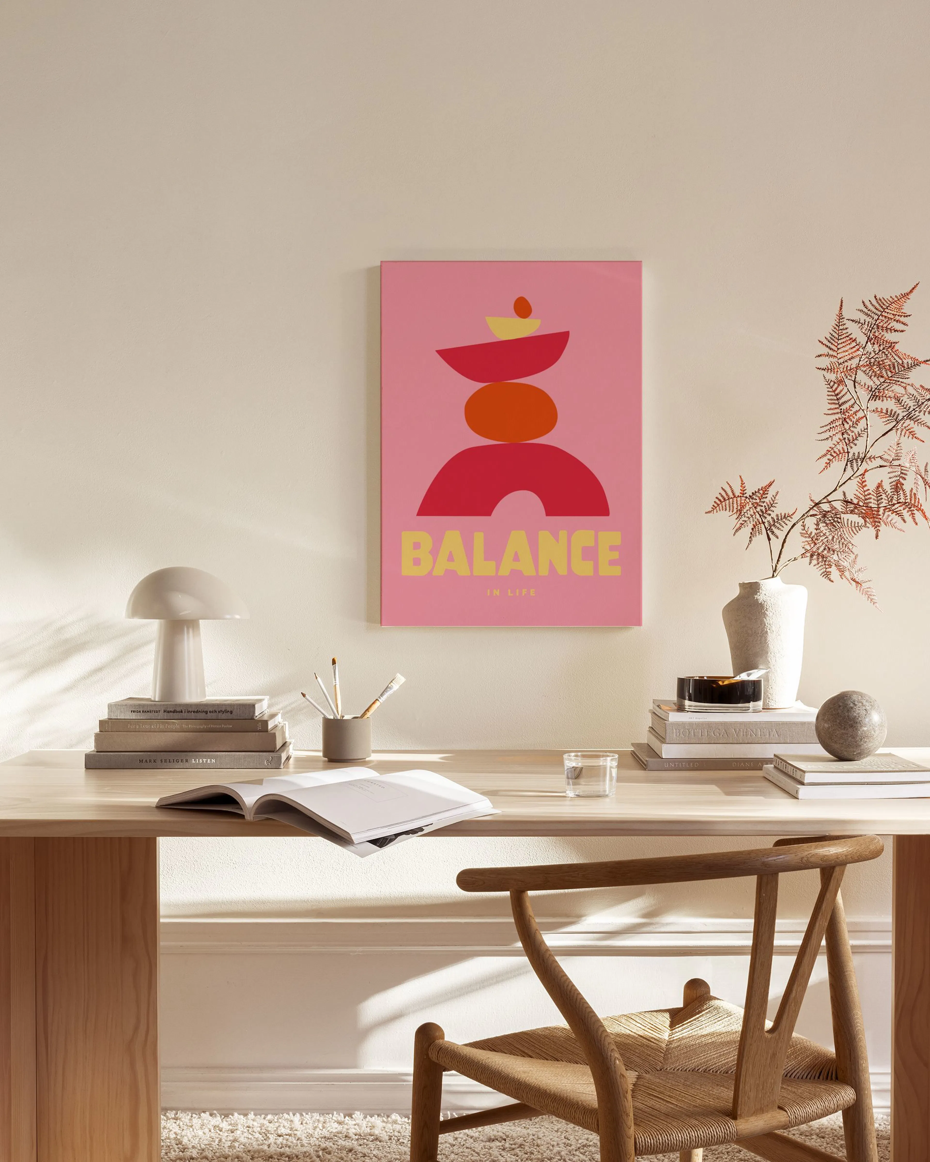 Lienzo moderno con formas abstractas rojas y naranjas sobre un fondo rosa, colgado en una sala de estar.
