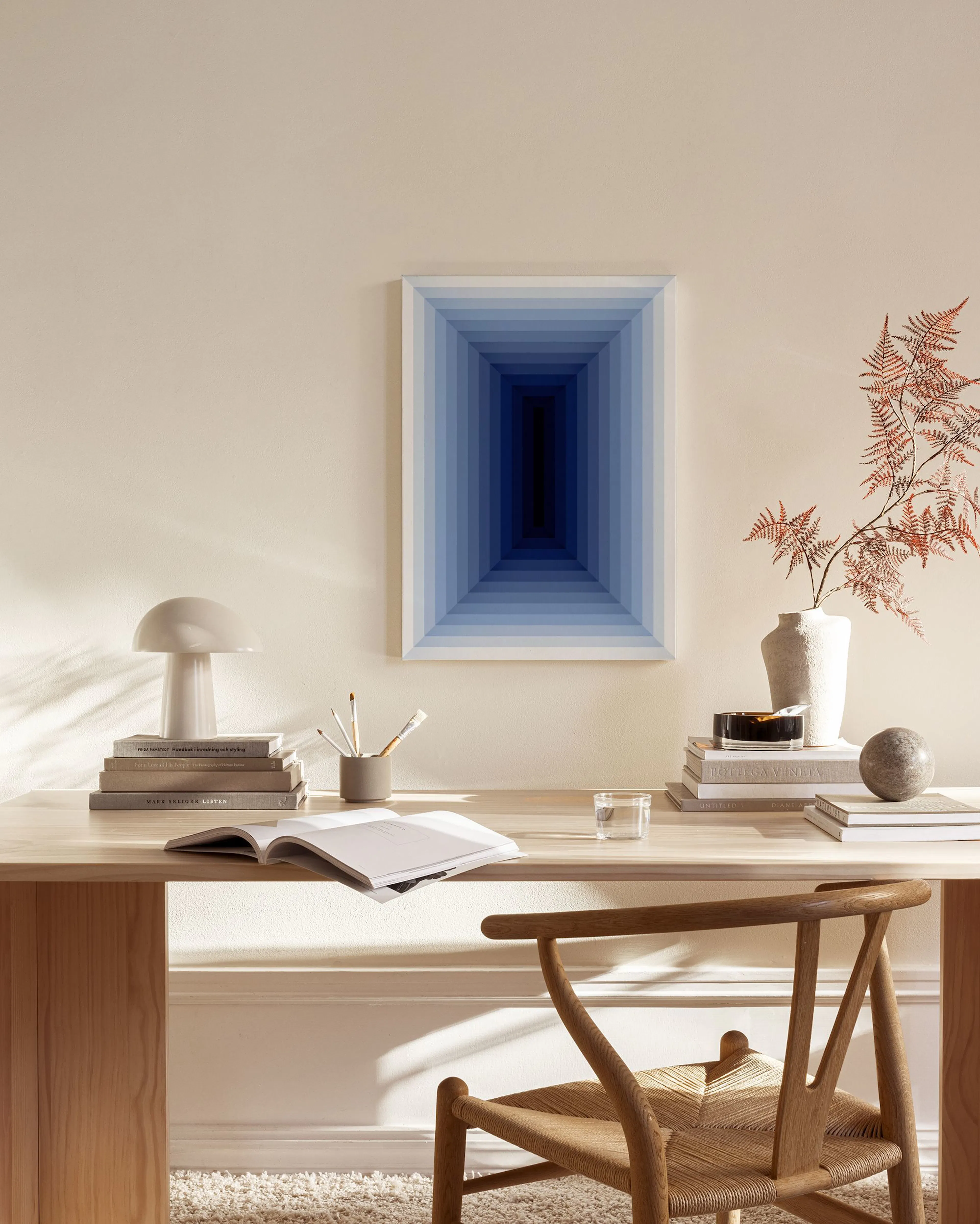 Canvas print featuring a blue gradient tunnel effect, hanging in a minimalist living room above a wooden console.
