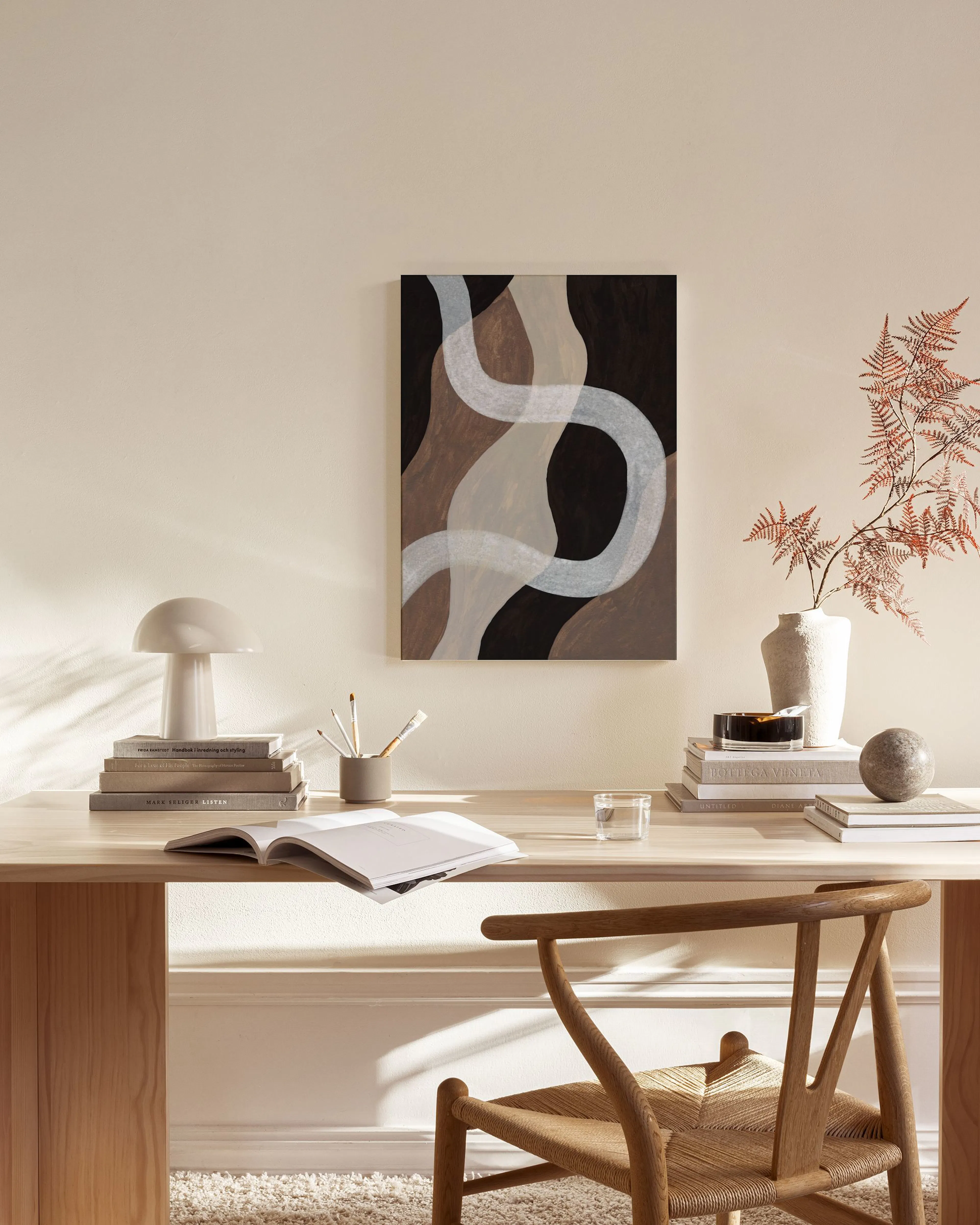Toile abstraite avec des formes organiques marron et noires, et des lignes ondulées blanches, dans un salon lumineux.