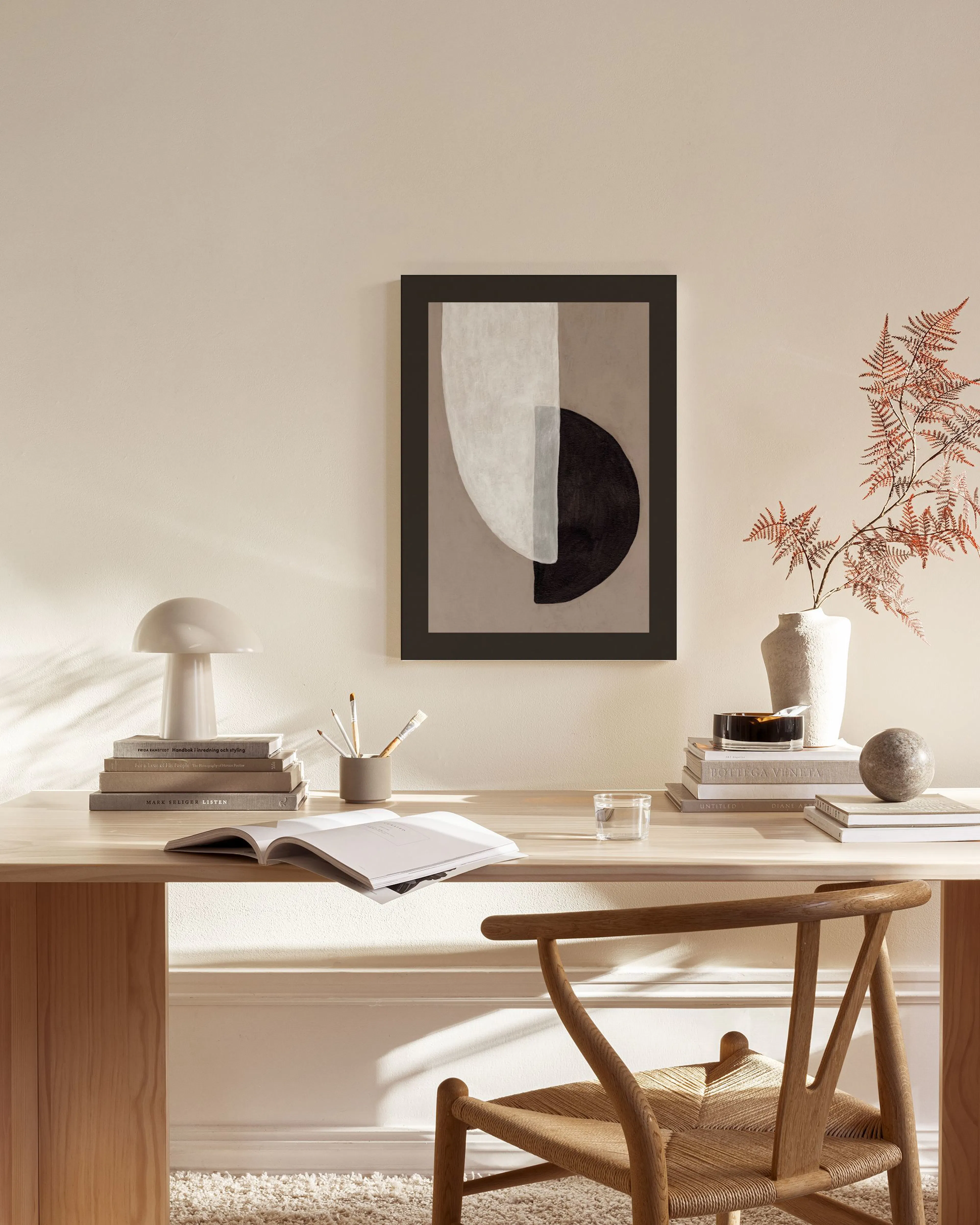 Obraz na plátně s abstraktními tvary v béžových, bílých a černých tónech, visící nad dřevěnou komodou v obývacím pokoji.