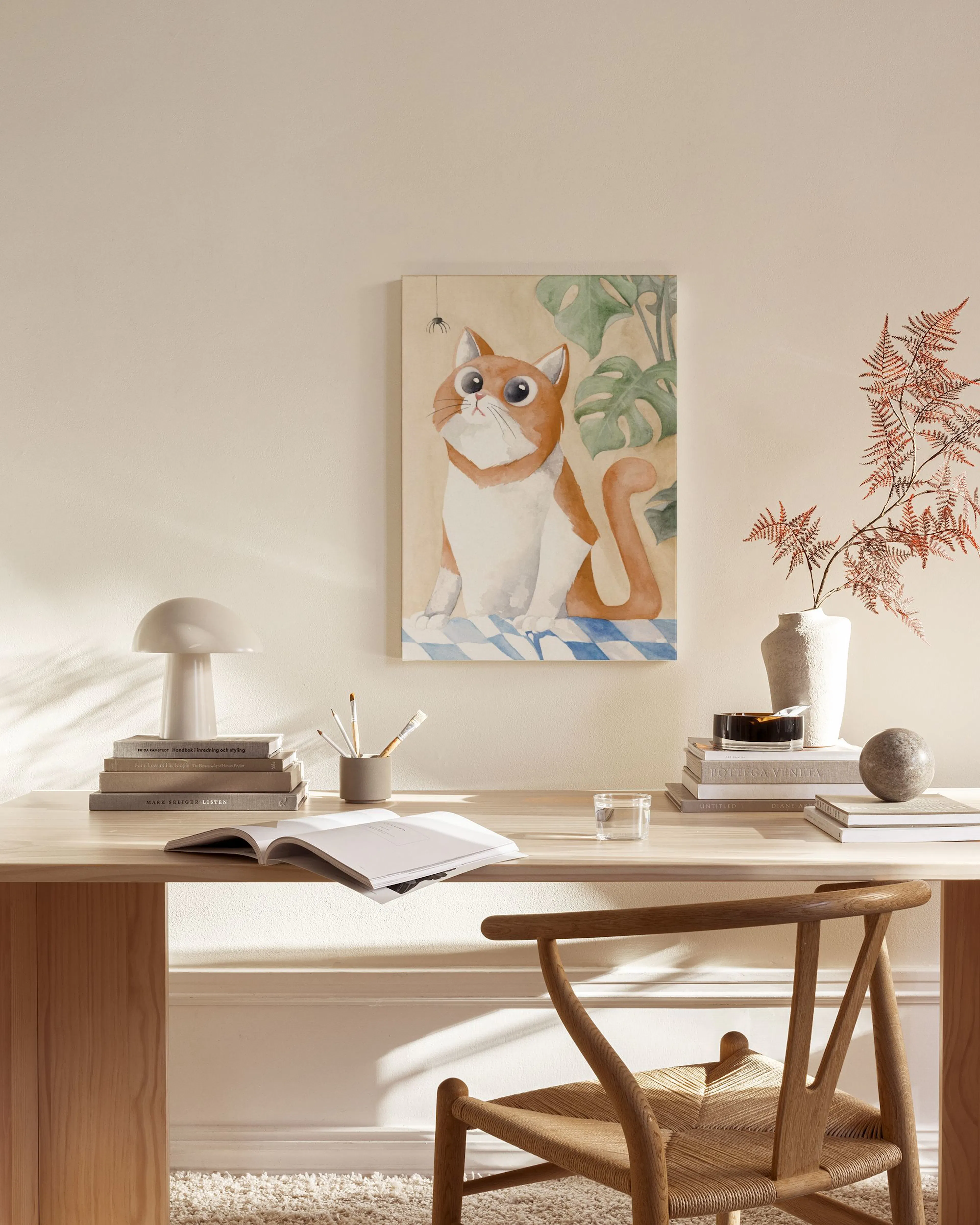 Canvas van een oranje-witte kat met grote ogen en een spinnetje, hangend in een moderne, minimalistische woonkamer.