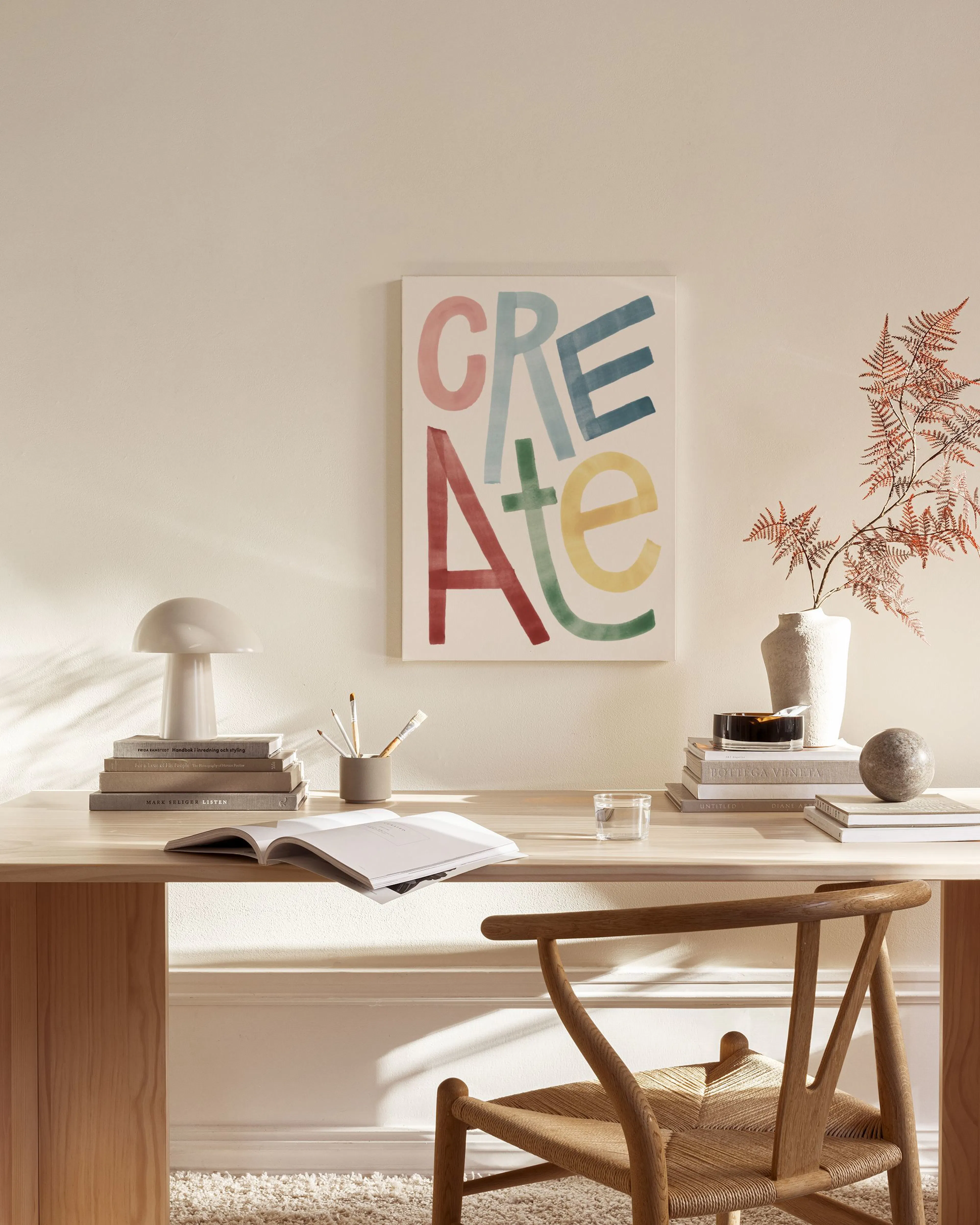 A canvas print with the word CREATE in colourful, varied fonts, displayed in a modern living room above a wooden console table.