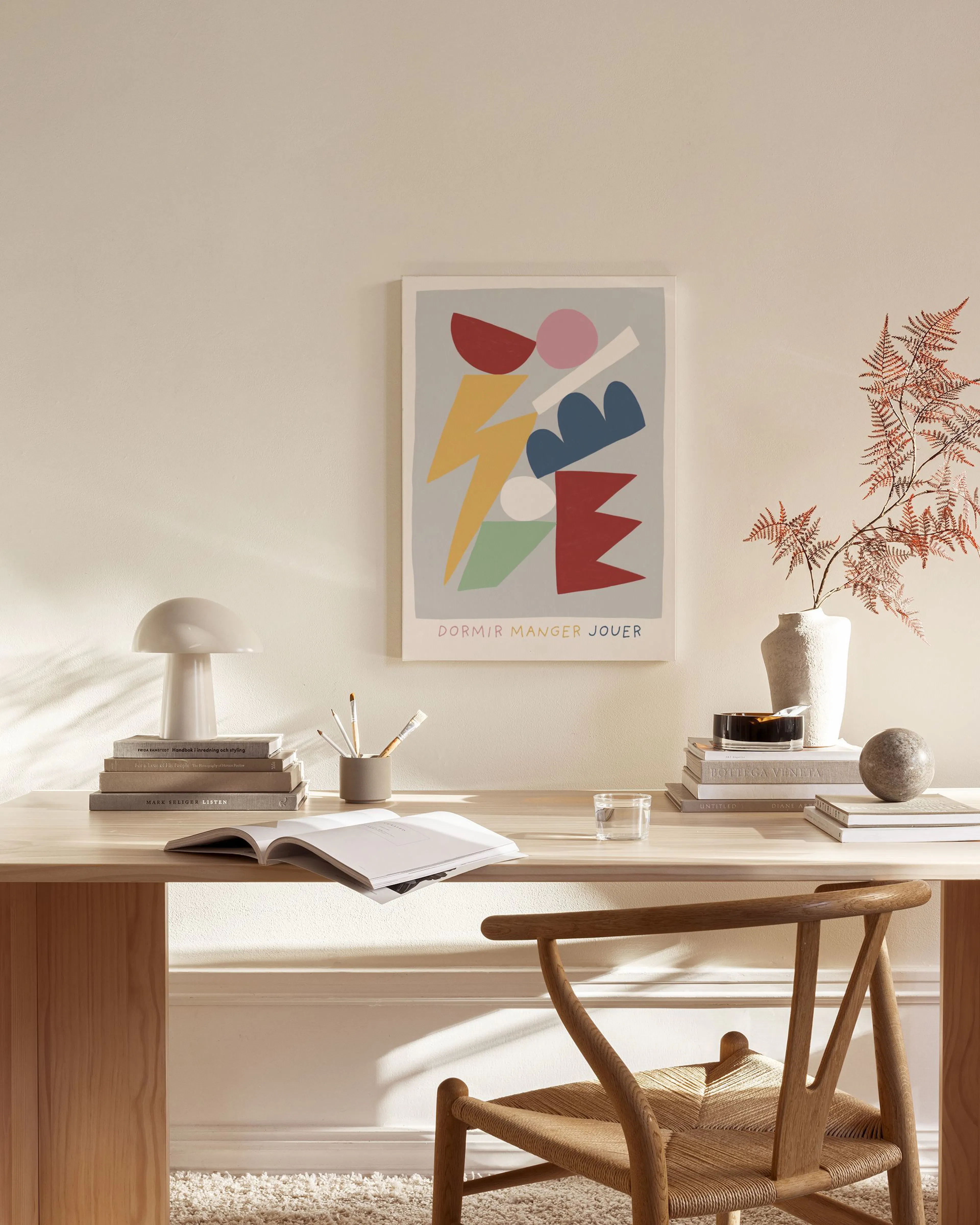 En canvastavla med färgstarka, abstrakta former på grå bakgrund, hängandes i ett ljust vardagsrum.