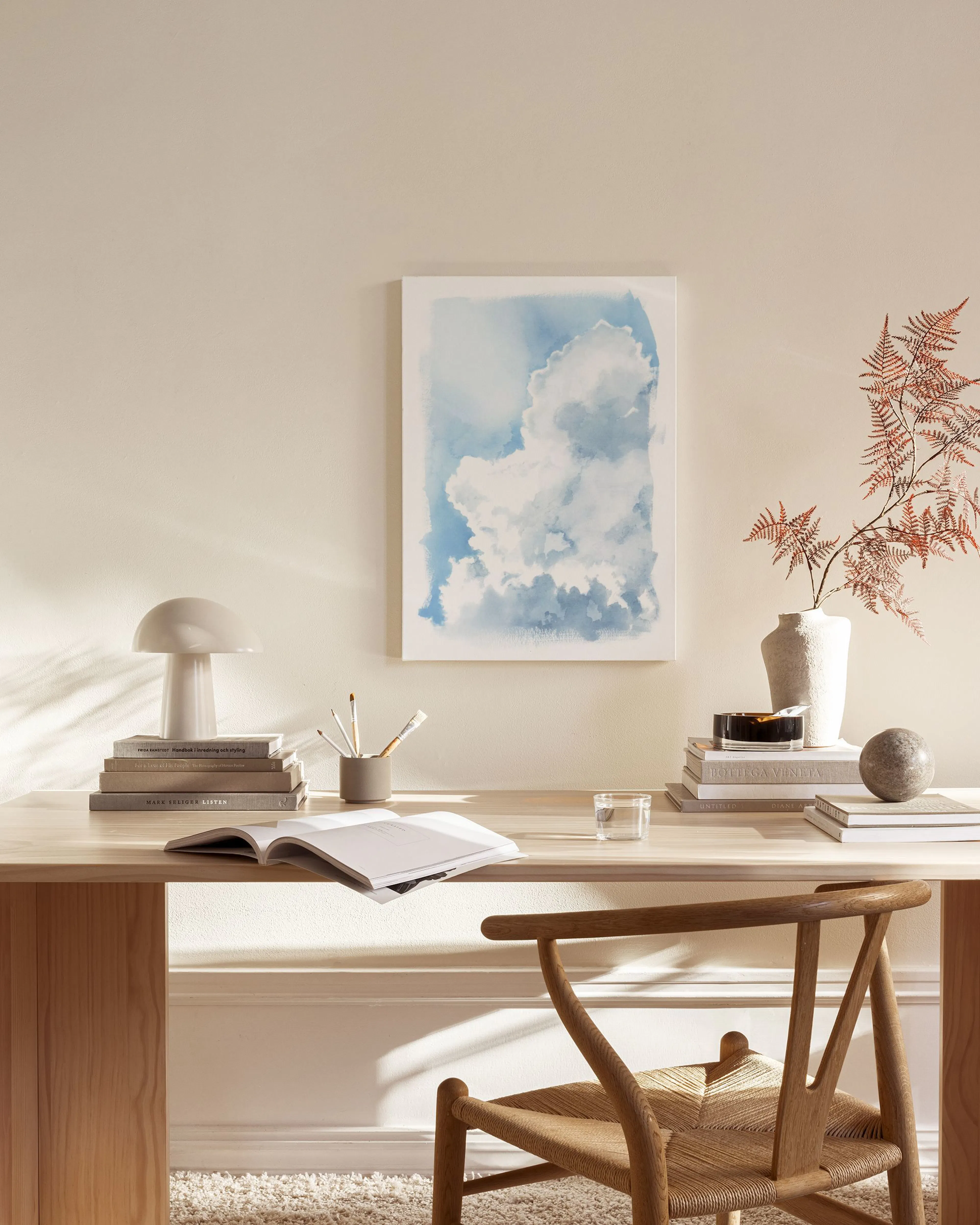 Toile murale abstraite de nuages bleus et blancs, suspendue dans un salon moderne aux tons neutres.