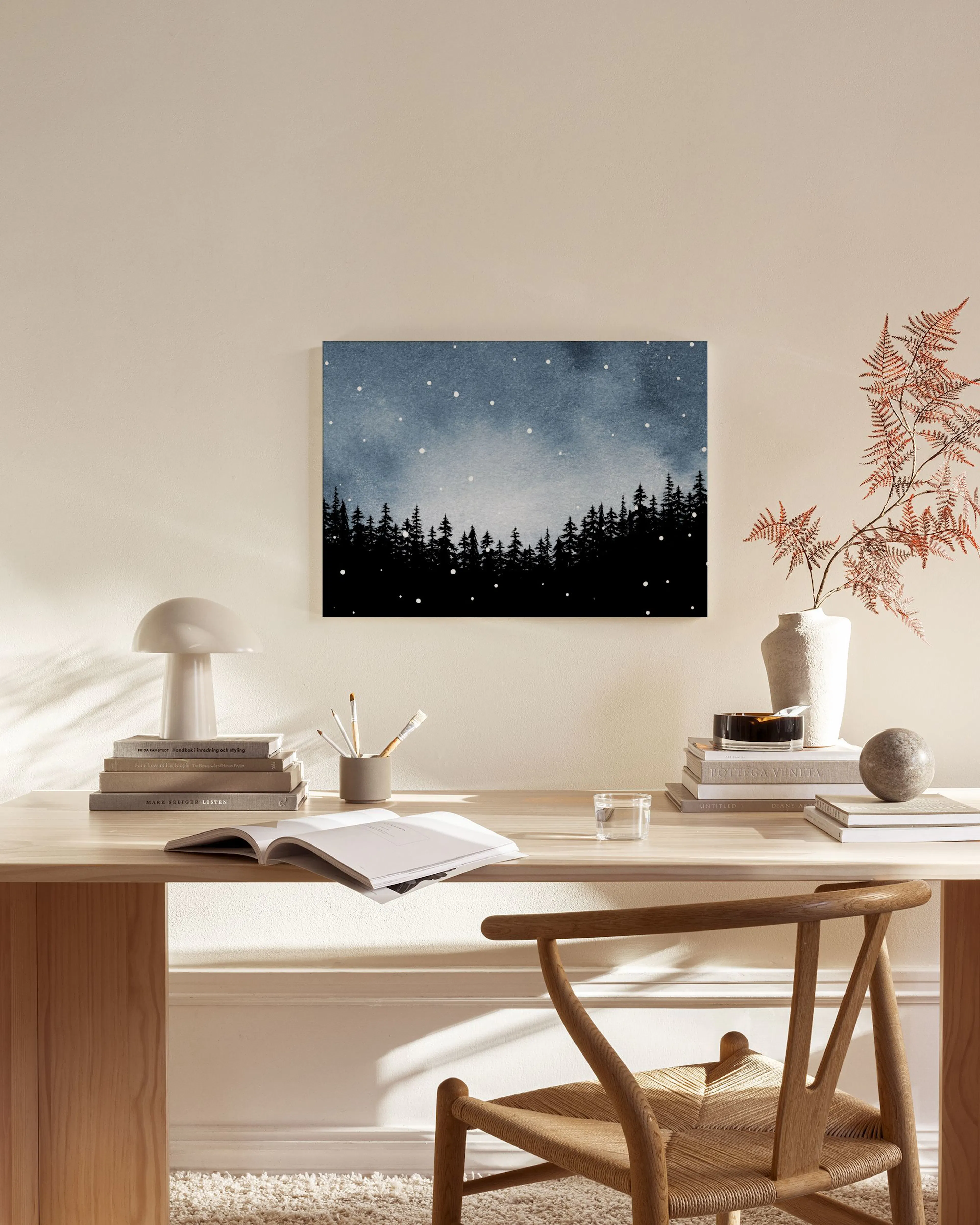 Leinwandbild mit schwarzer Waldsilhouette vor sternklarem, dunkelblauem Himmel, hängend über einem Sideboard im Wohnzimmer.