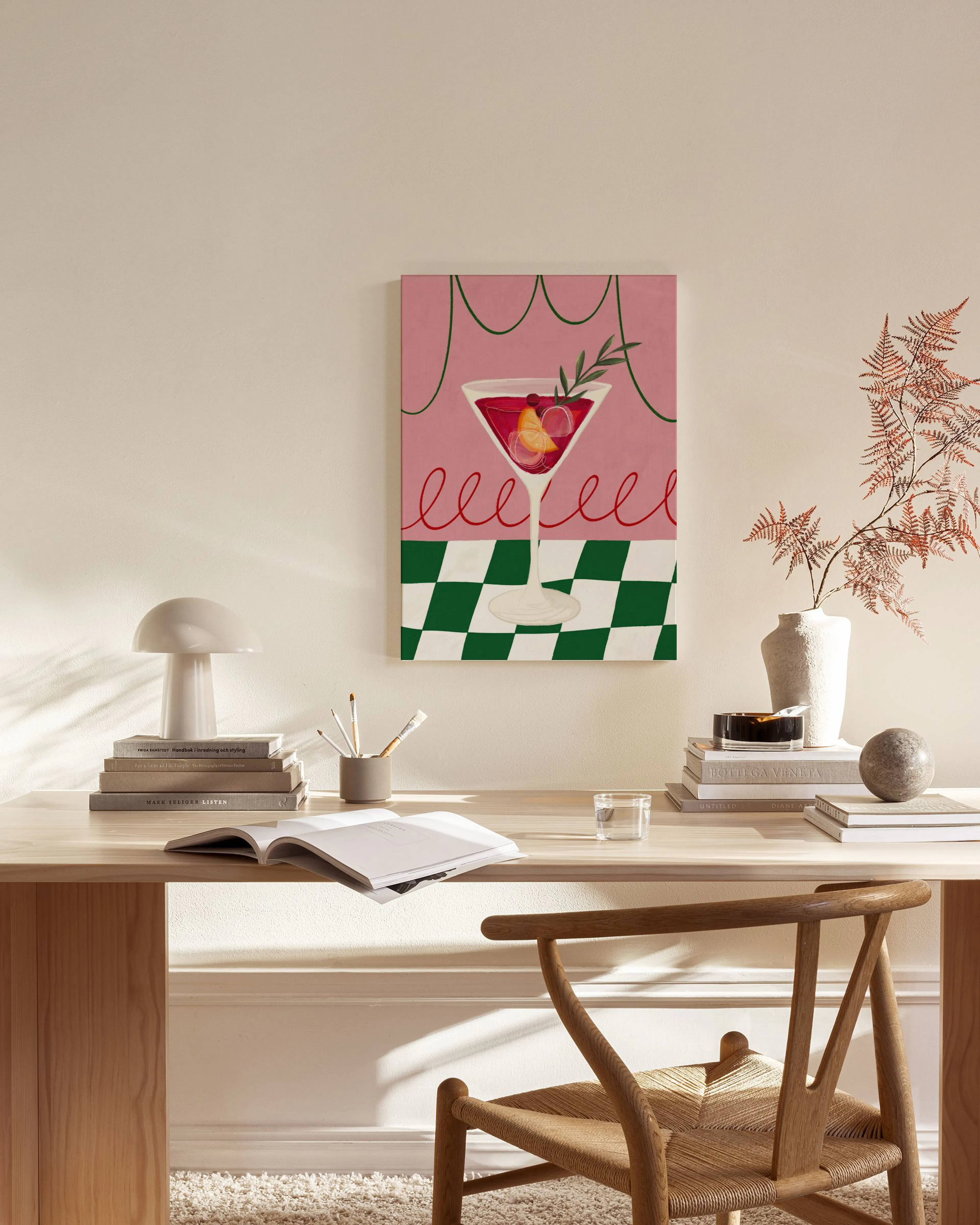 Canvas van een rode cocktail met fruit en olijftak op een roze achtergrond met groen schaakbordpatroon, hangend in een moderne w