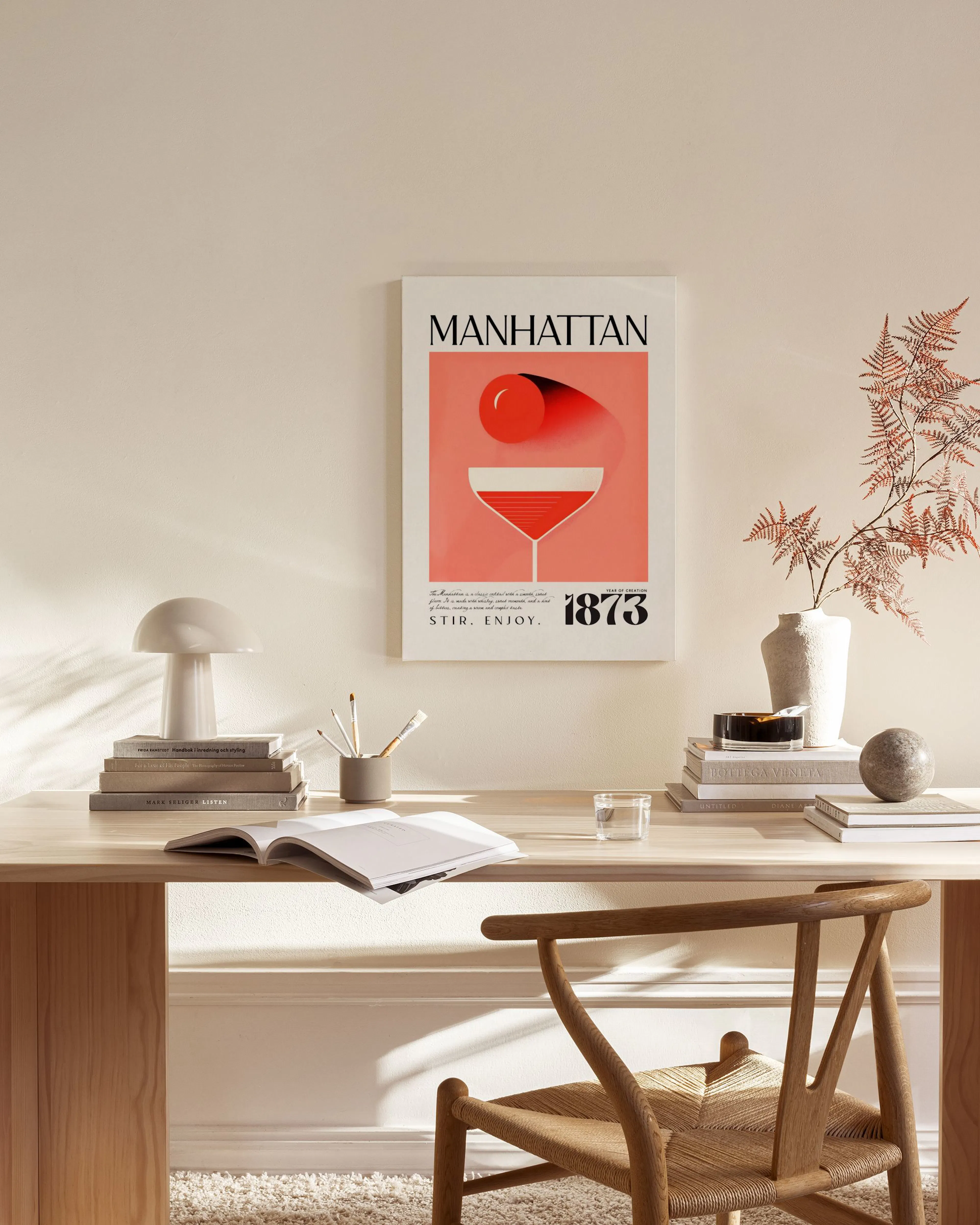 Canvastavla med illustration av en Manhattan-cocktail i rött och orange, hängande i ett ljust vardagsrum.
