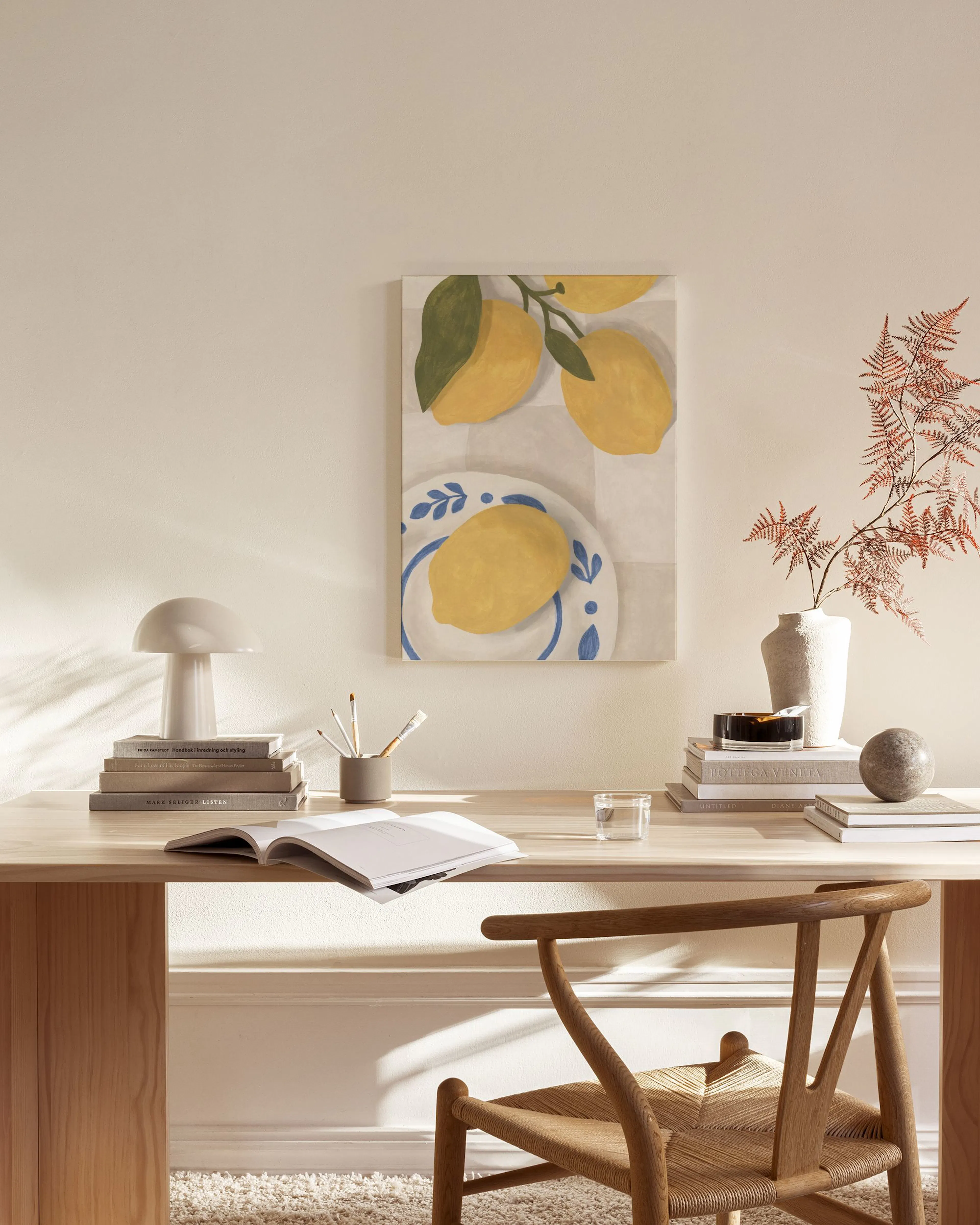 Canvas met citroenen en een bord met blauwe details, hangend in een rustige woonkamer boven een houten dressoir.