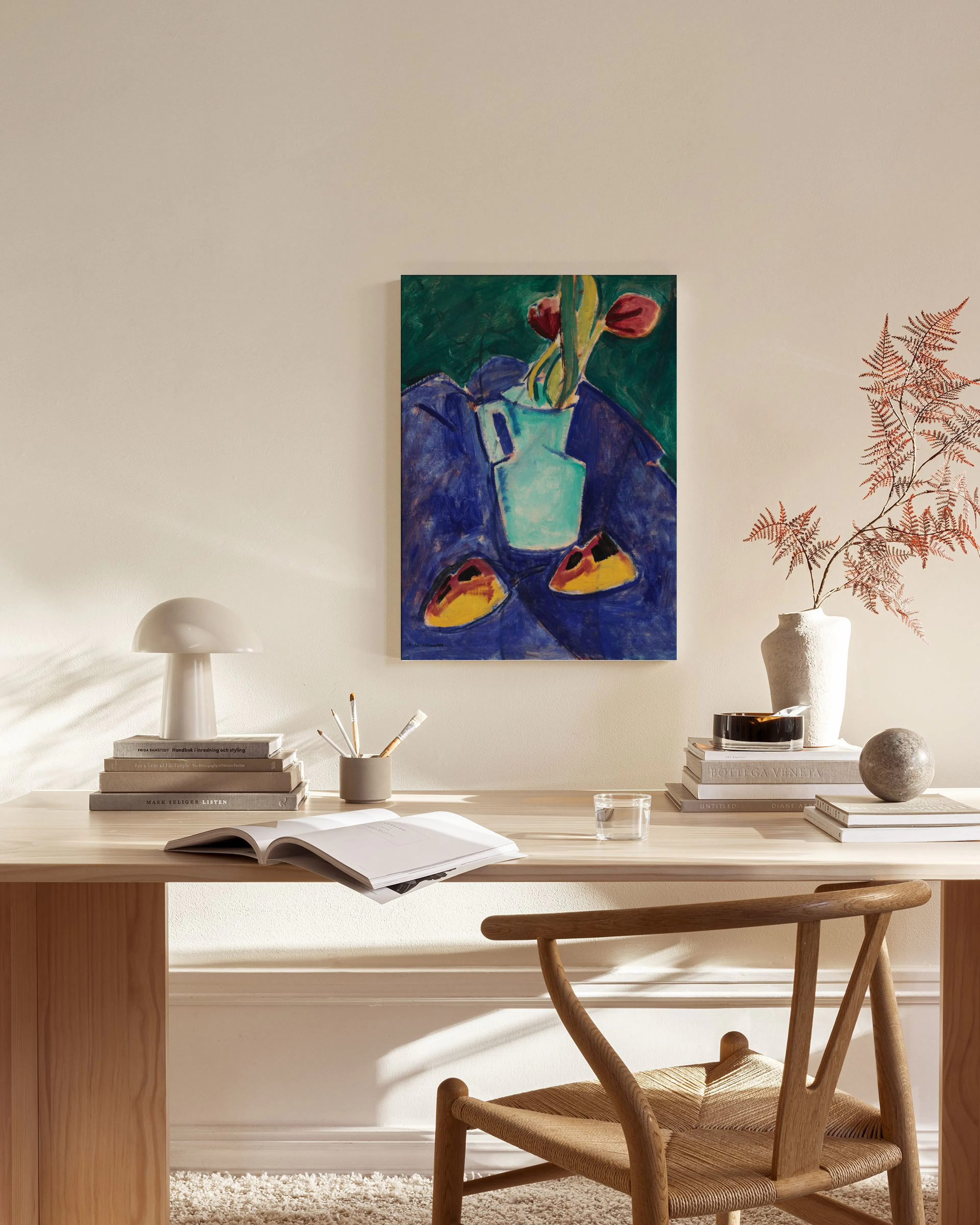 Stampa su tela di un vaso azzurro con fiori rossi su sfondo blu e verde, appesa in un soggiorno moderno.