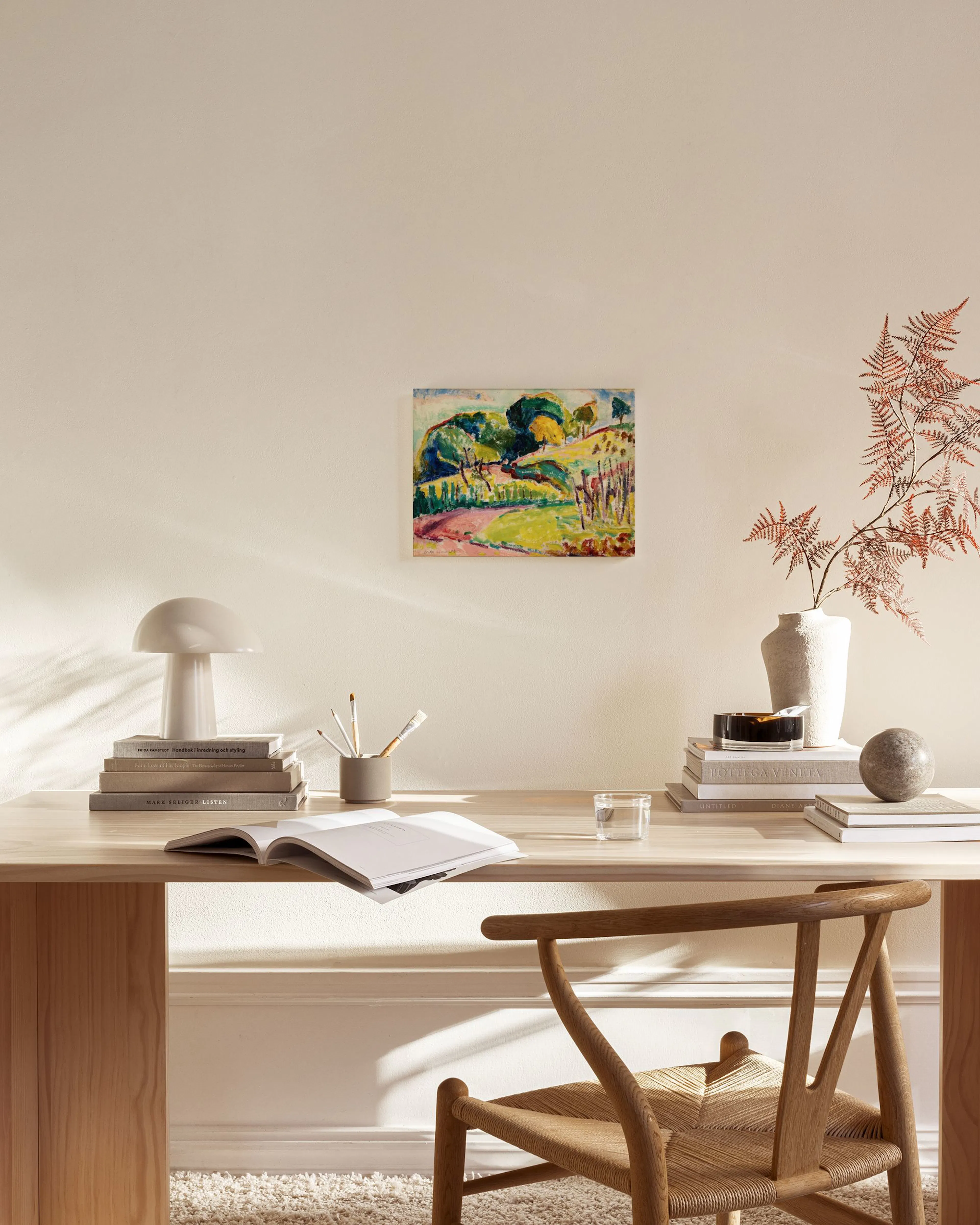 Vibrant landscape canvas print with green, yellow, and red hues, depicting trees and a path, displayed in a modern living room.