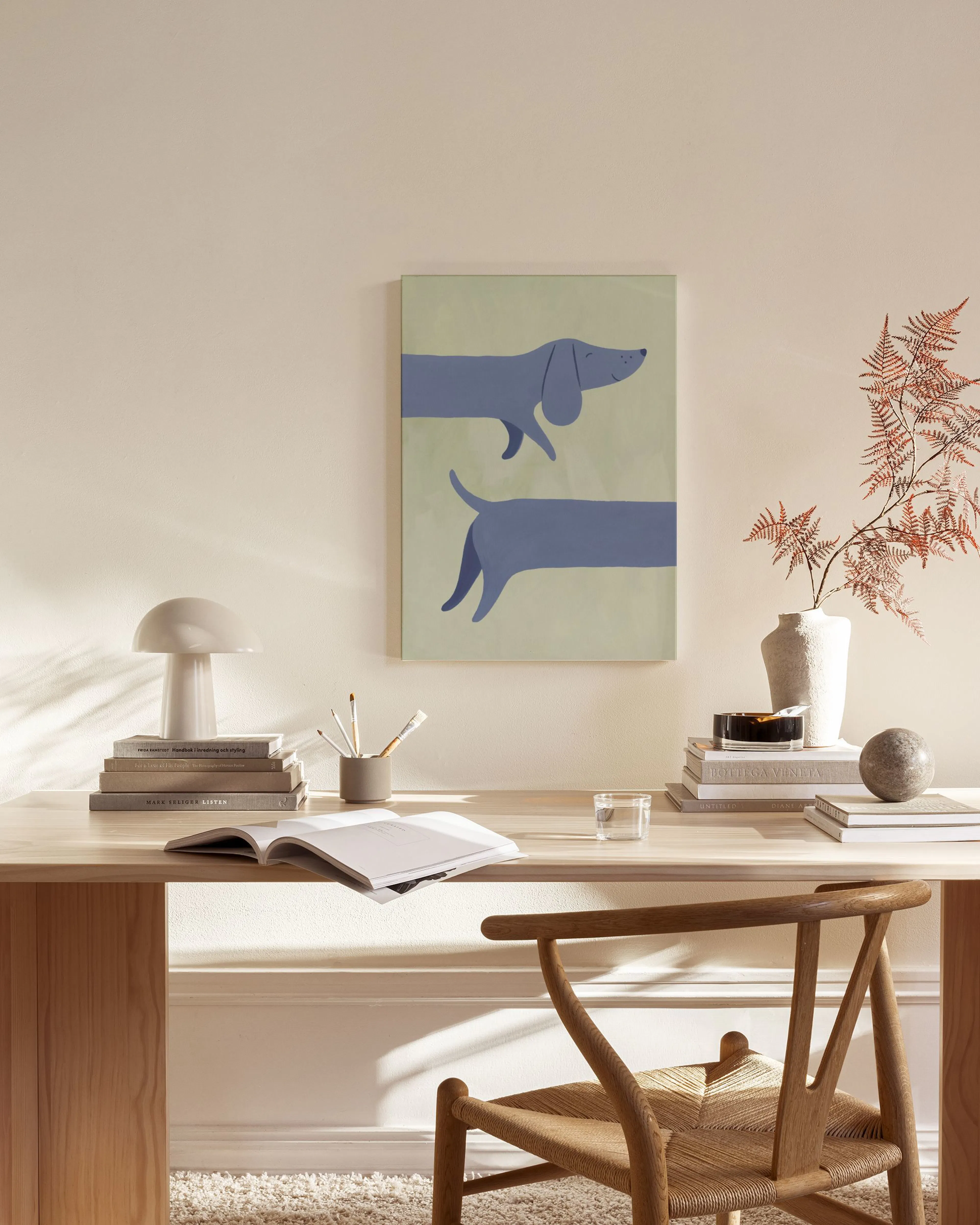 Leinwandbild mit zwei stilisierten blauen Dackeln auf hellgrünem Hintergrund, hängend in einem modernen Wohnzimmer.