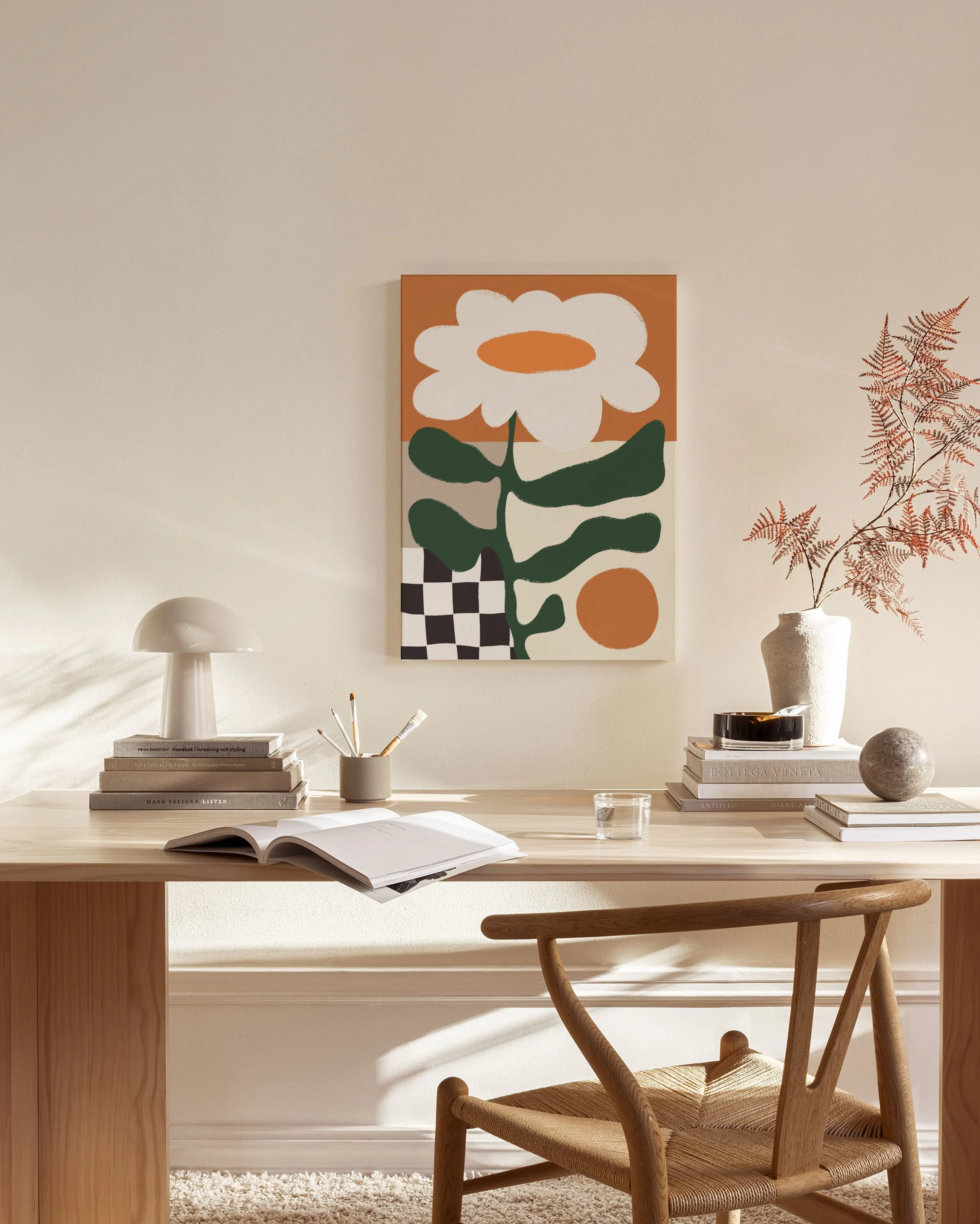 Toile dart abstrait floral avec des formes blanches, vertes et marron sur fond orange, accrochée dans un salon moderne.
