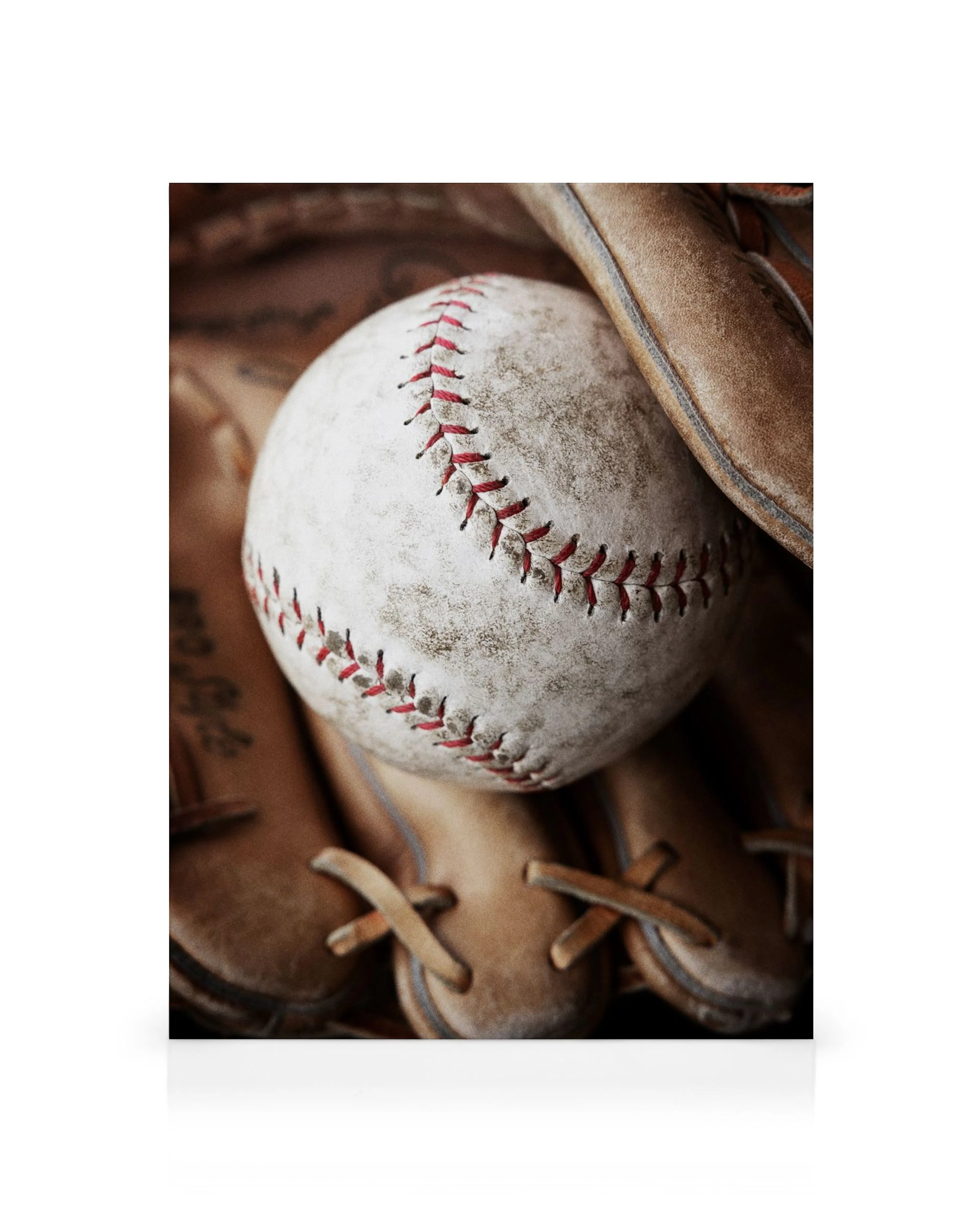 Nahaufnahme eines altmodischen Baseballhandschuhs aus Leder mit einem Baseball und roten Nähten
