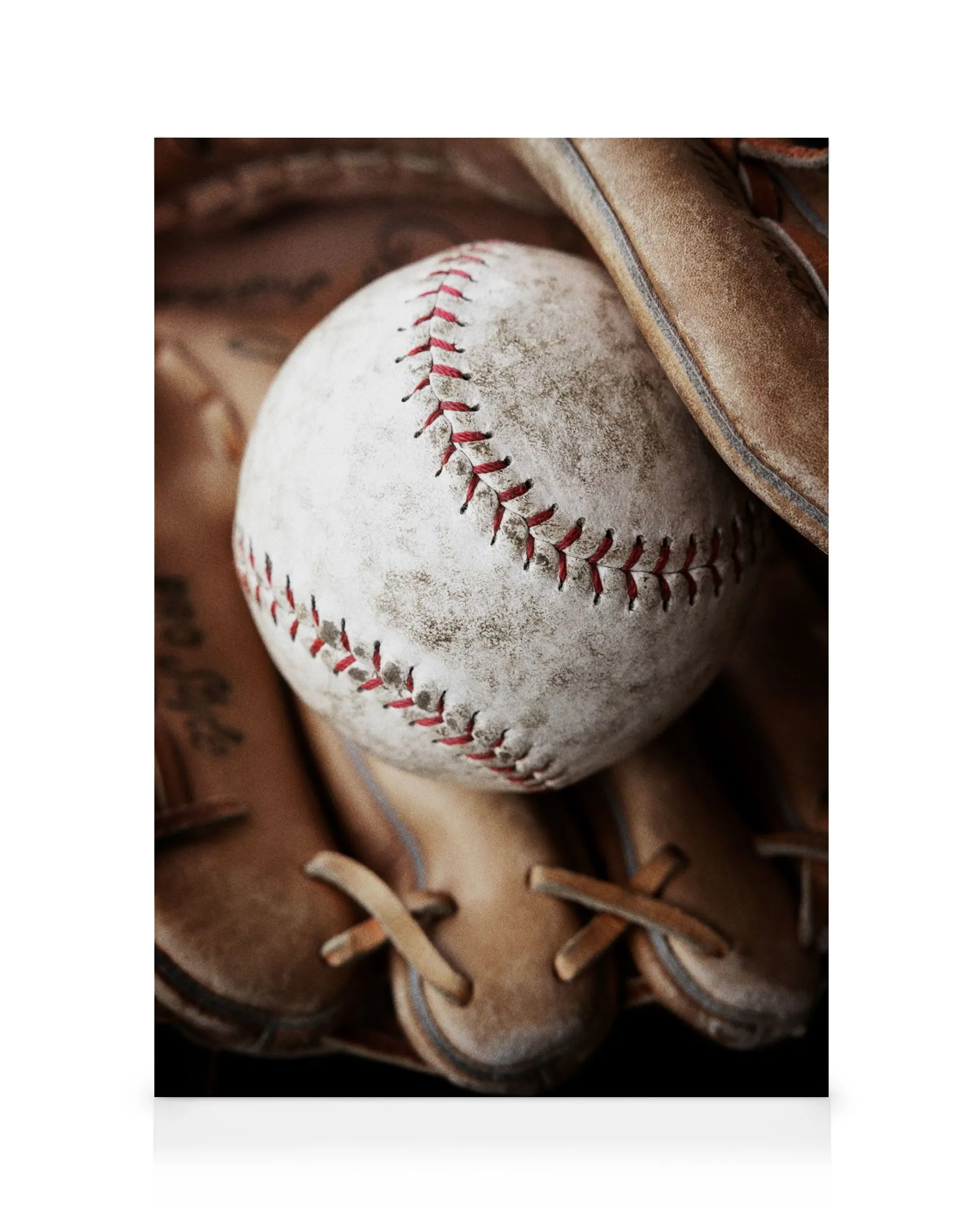 Baseballový míč v hnědé kožené rukavici, detaily švů a textury.