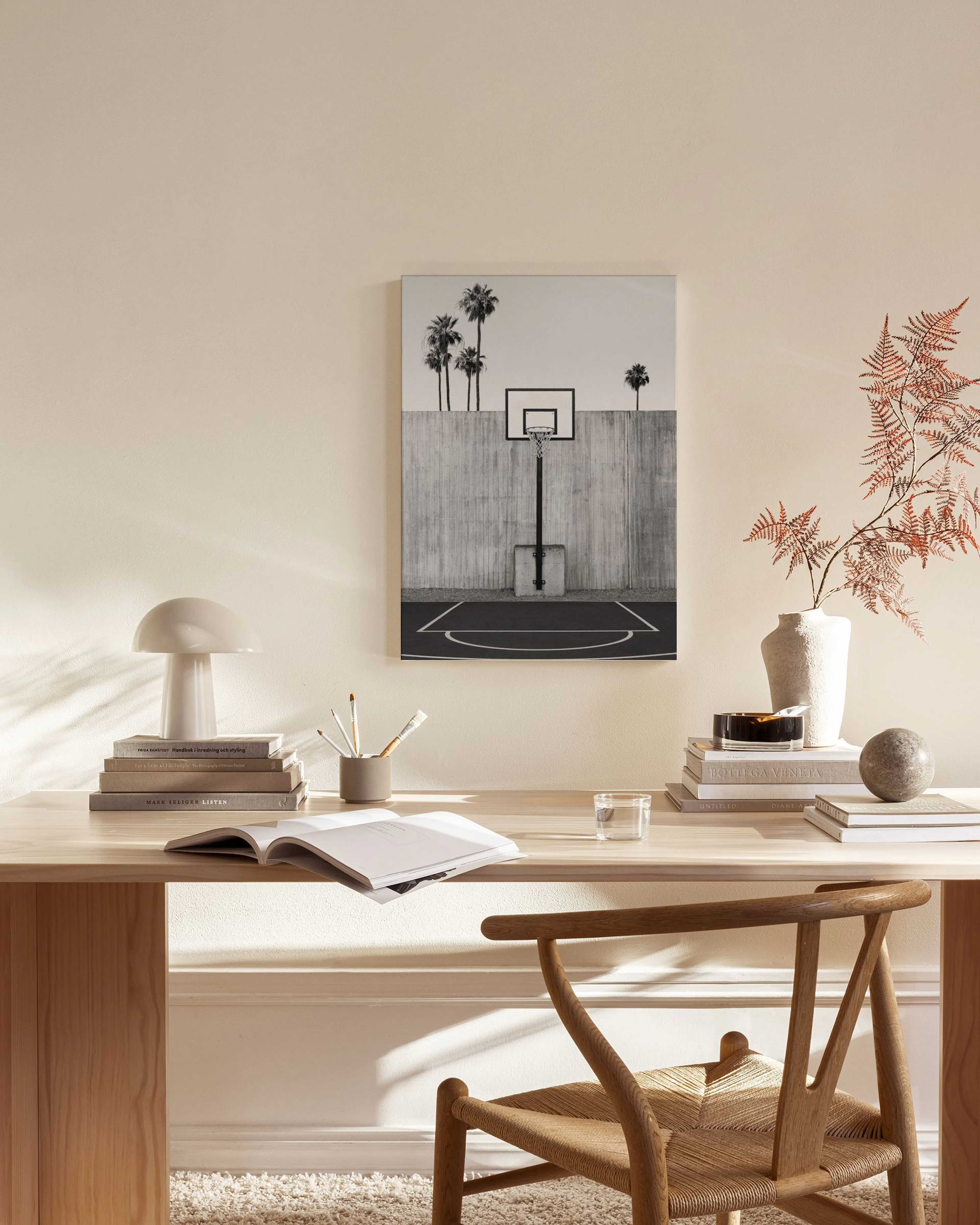 Leinwandbild eines Basketballplatzes mit Palmen in Schwarz-Weiß, hängend in einem hellen Wohnzimmer über einem Sideboard.