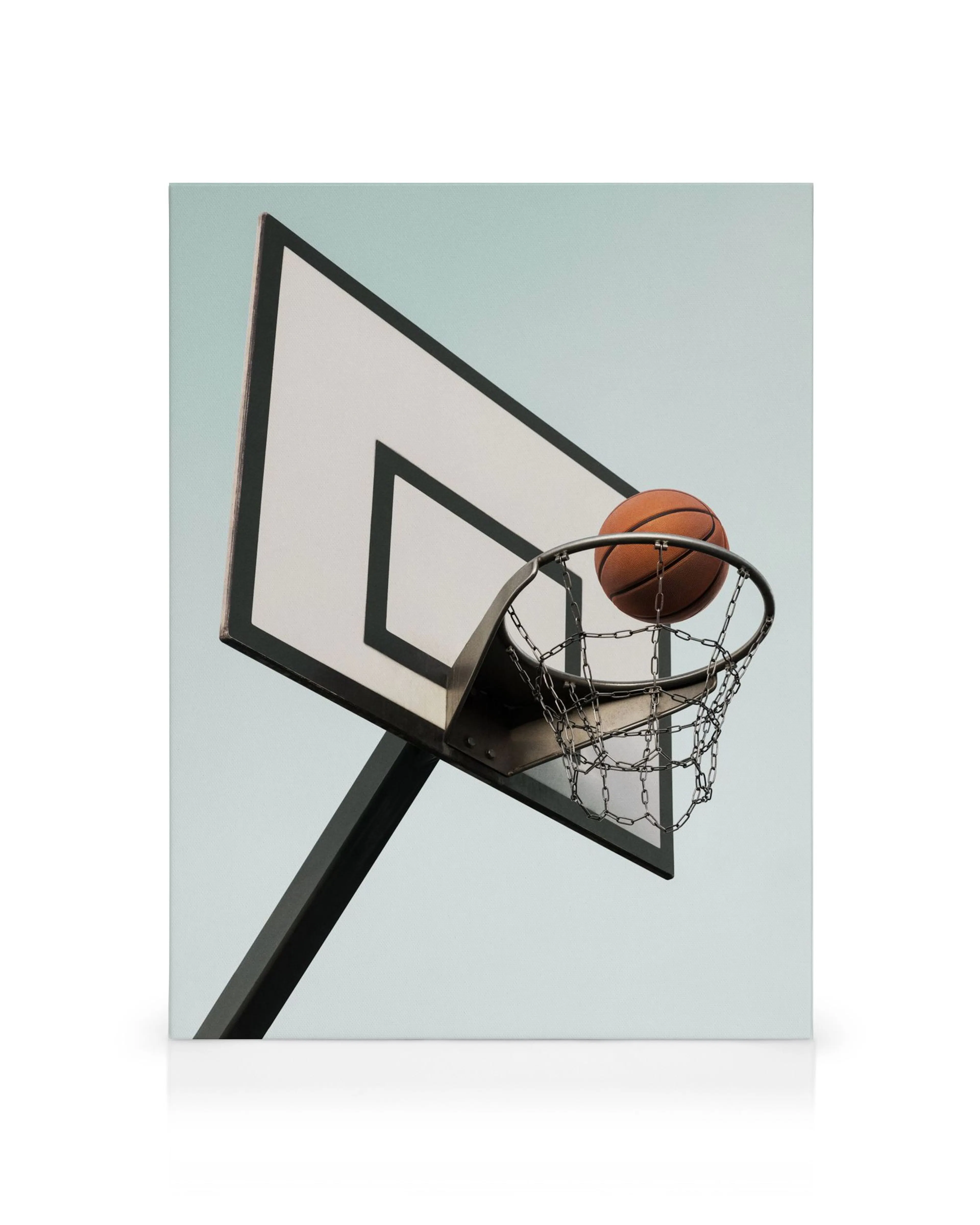 Basketball balancing on rim of hoop with chain net against light blue background, canvas print
