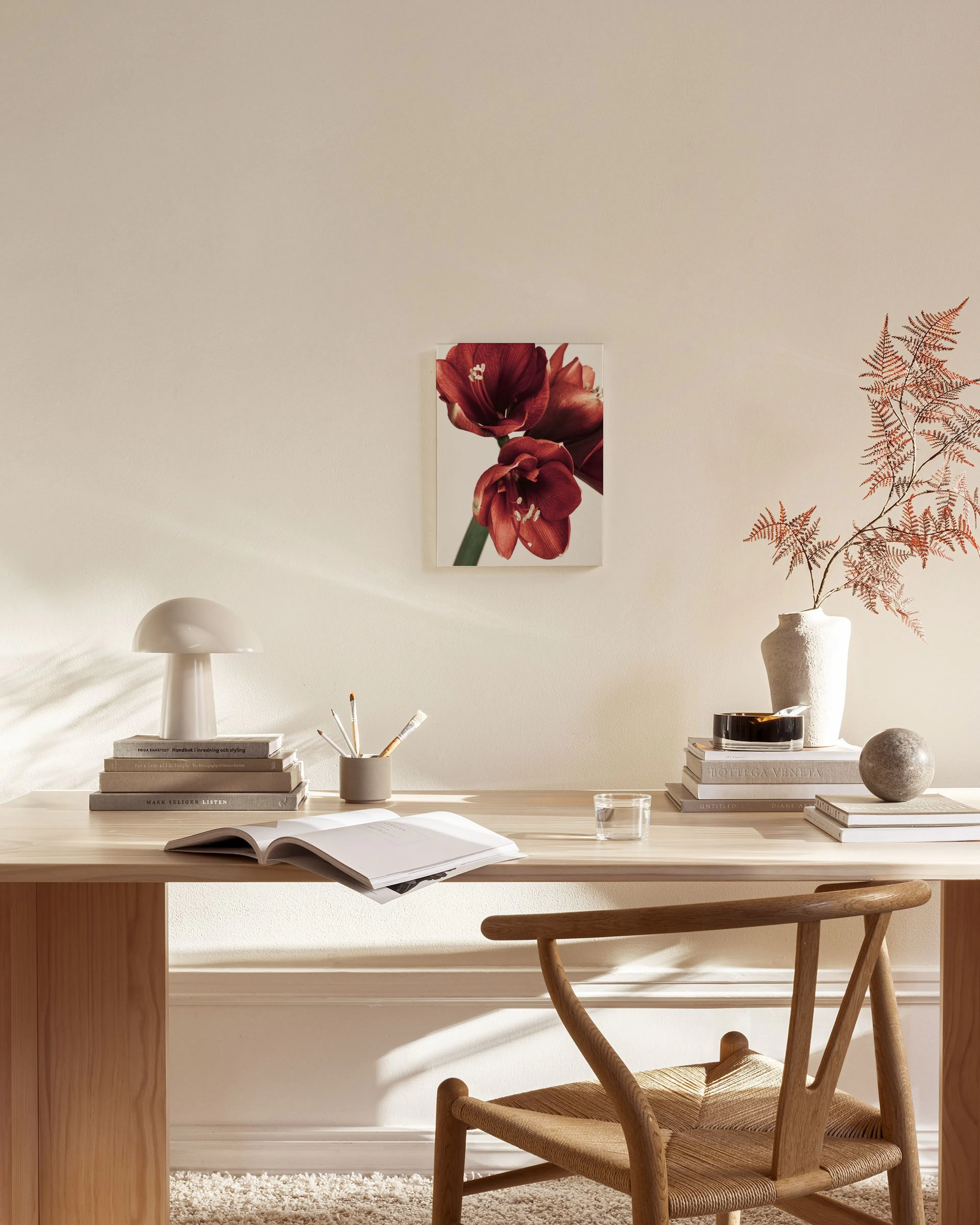 Lienzo con tres flores de amarilis rojas intensas, colgando sobre un aparador de madera en una sala de estar moderna.