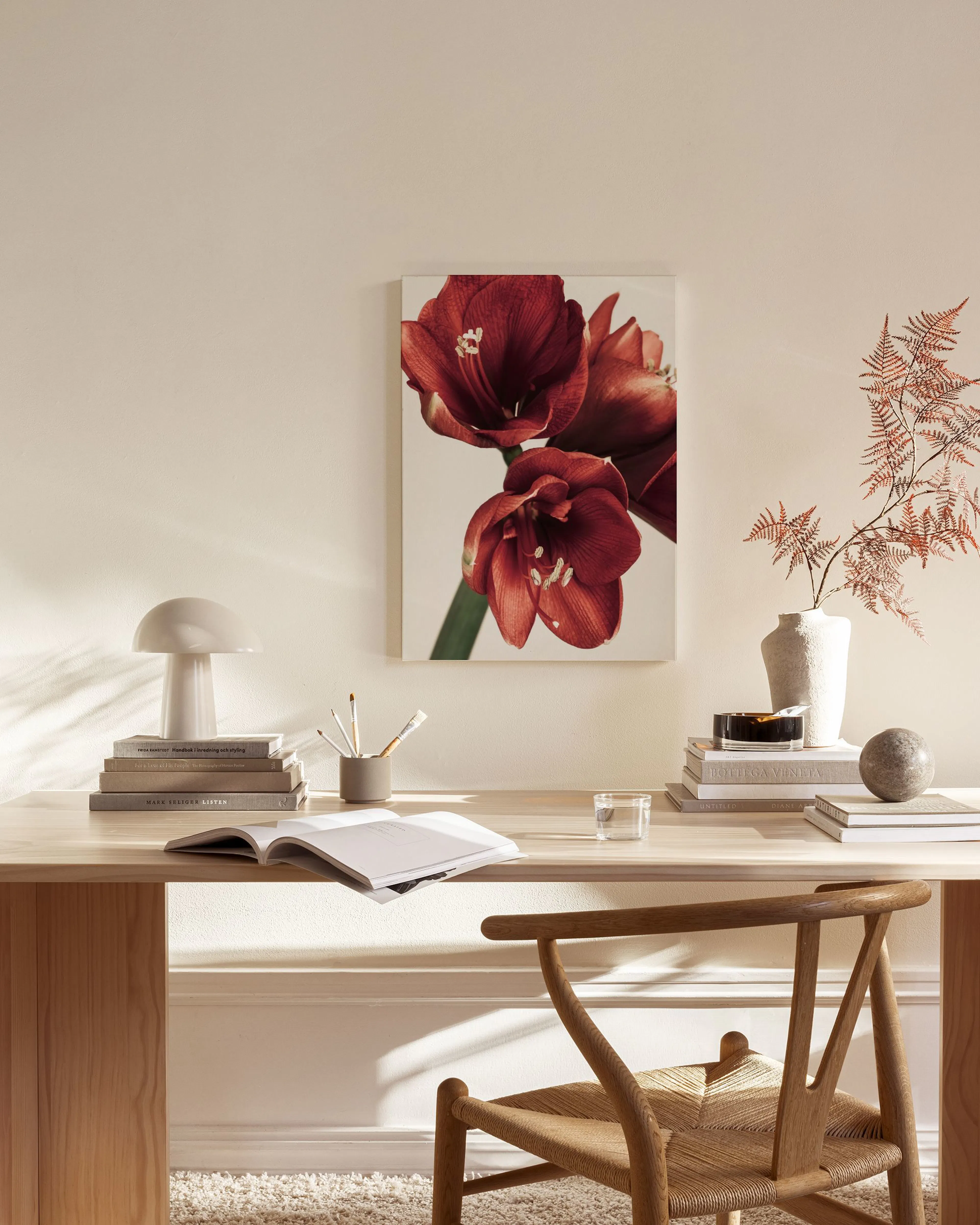 Leinwandbild mit roten Amaryllisblüten an einer hellen Wand über einer Anrichte in einem Wohnzimmer.