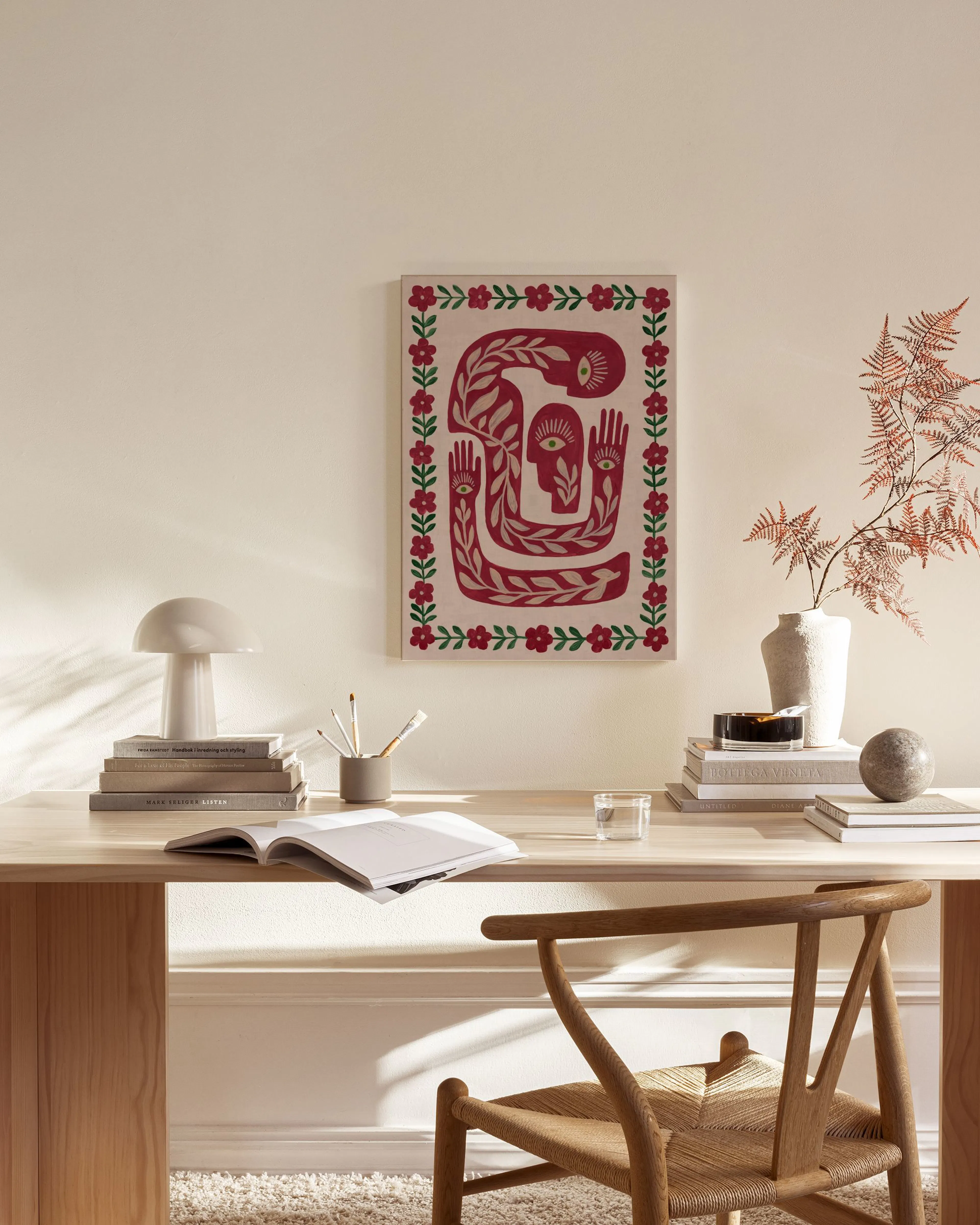 Leinwandbild mit rotem, organischem Muster und Blumenrahmen, hängend über einem Sideboard in einem Wohnzimmer.